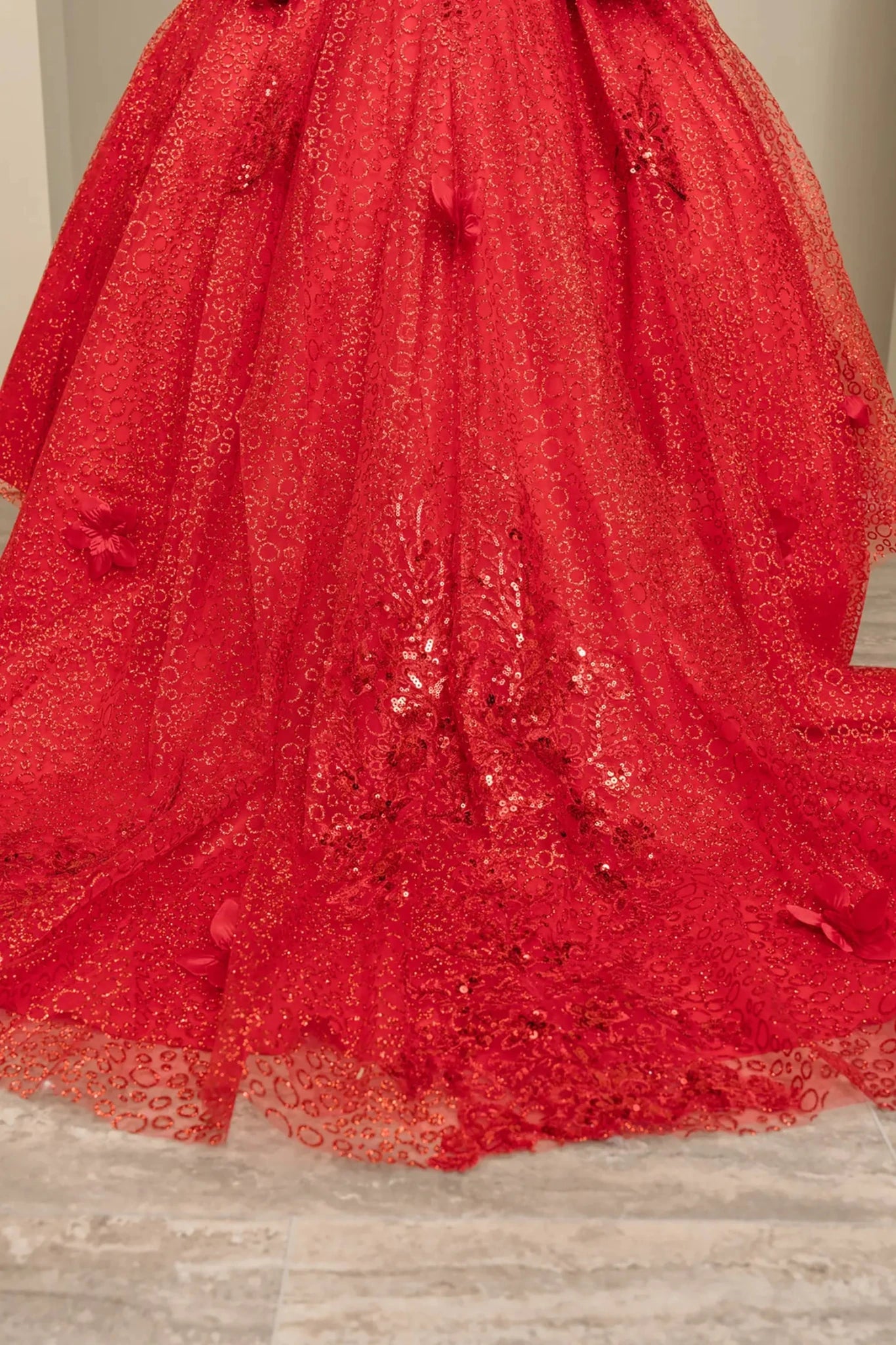 Bodice close-up of a red kids quinceañera dress with floral embroidery, sequins, and lace-up corset detail.