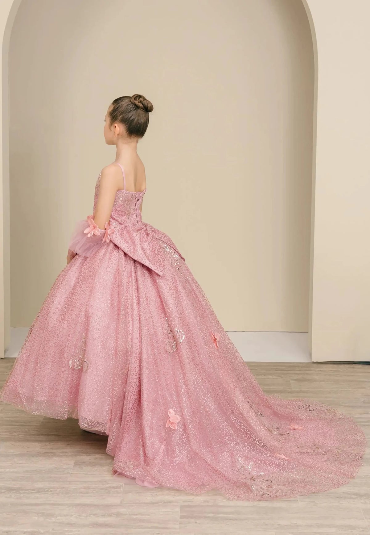 Side full-length view of Dusty Rose mini quince mini quince dress with glitter floral embroidered bodice, full skirt, lace up back, oversized bow, and sheer lace gloves.