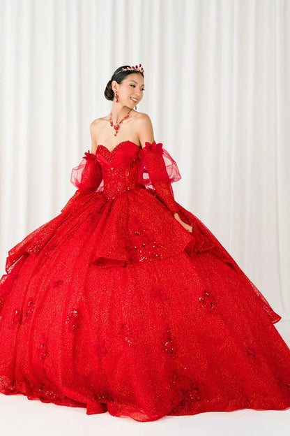 Rear view of a woman wearing red quinceañera dress with voluminous glitter tulle skirt, lace-up corset closure, and floral applique embellishments.