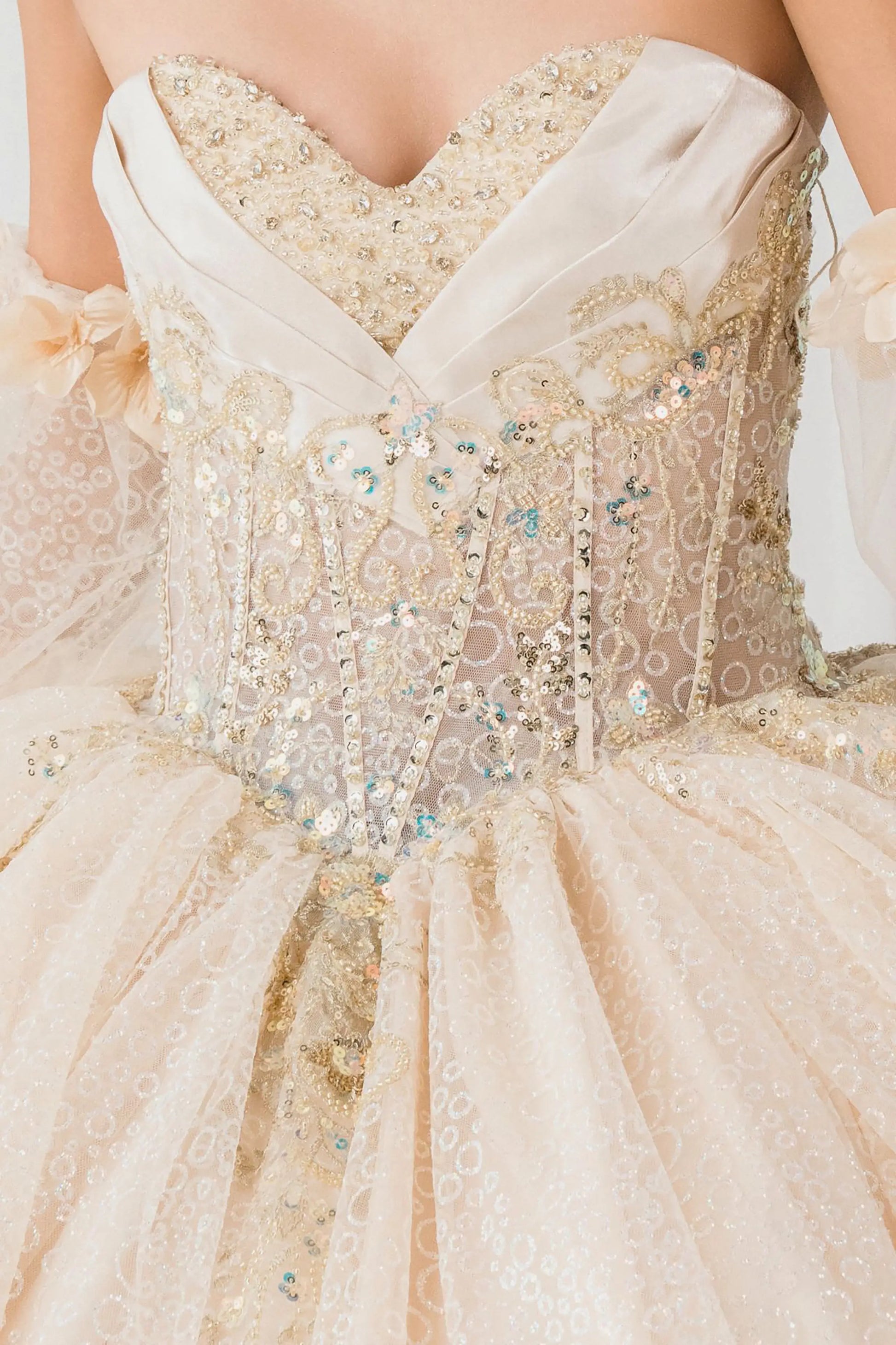 Front close-up Champagne quinceañera ball gown with off shoulder tulle sleeves, sweetheart sequin bodice, layered glitter tulle skirt, and cathedral train
