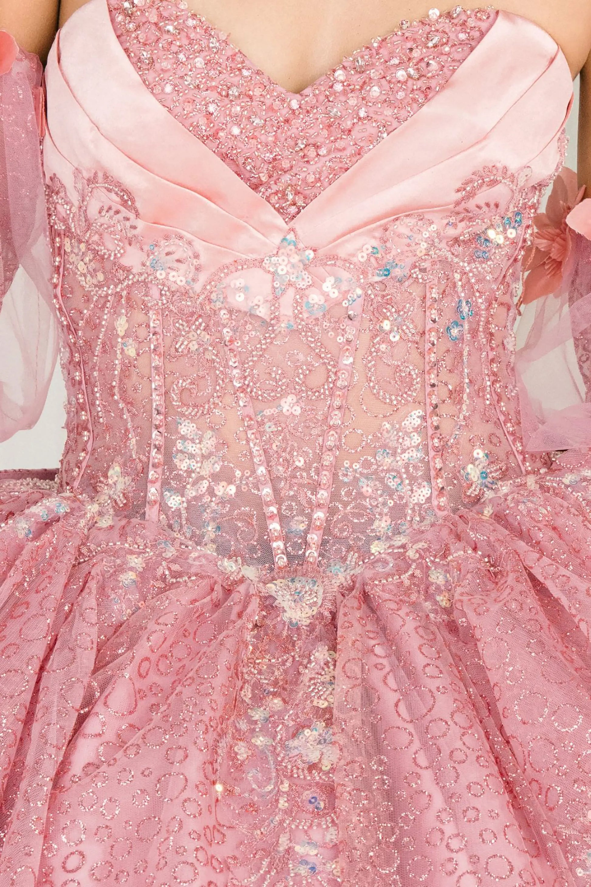 Front close-up Dusty Rose quinceañera ball gown with off shoulder tulle sleeves, sweetheart sequin bodice, layered glitter tulle skirt, and cathedral train