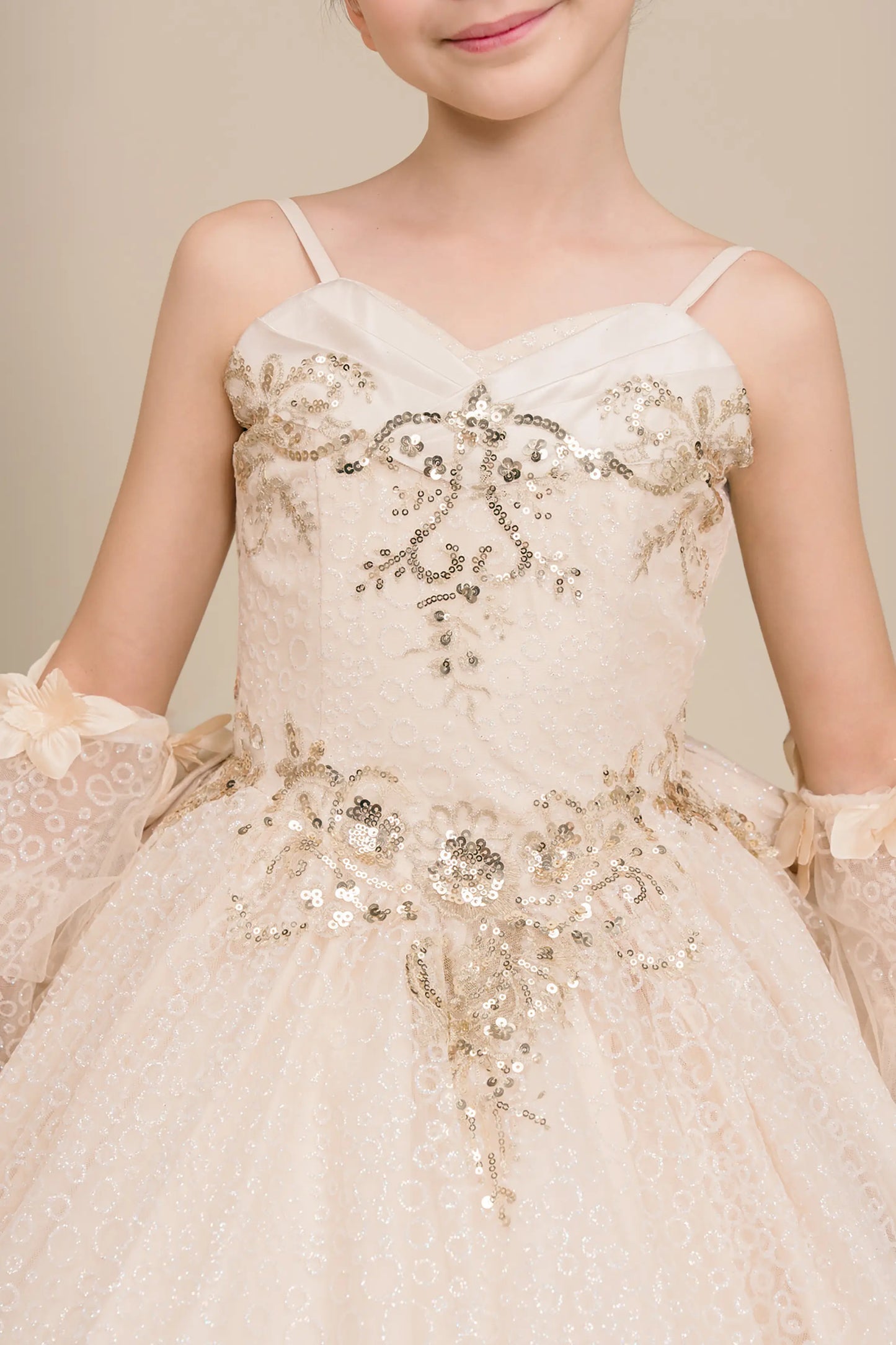 Front close up view of Champagne mini quince ball gown with glitter floral embroidered bodice, full skirt, lace up back, oversized bow, and sheer lace gloves