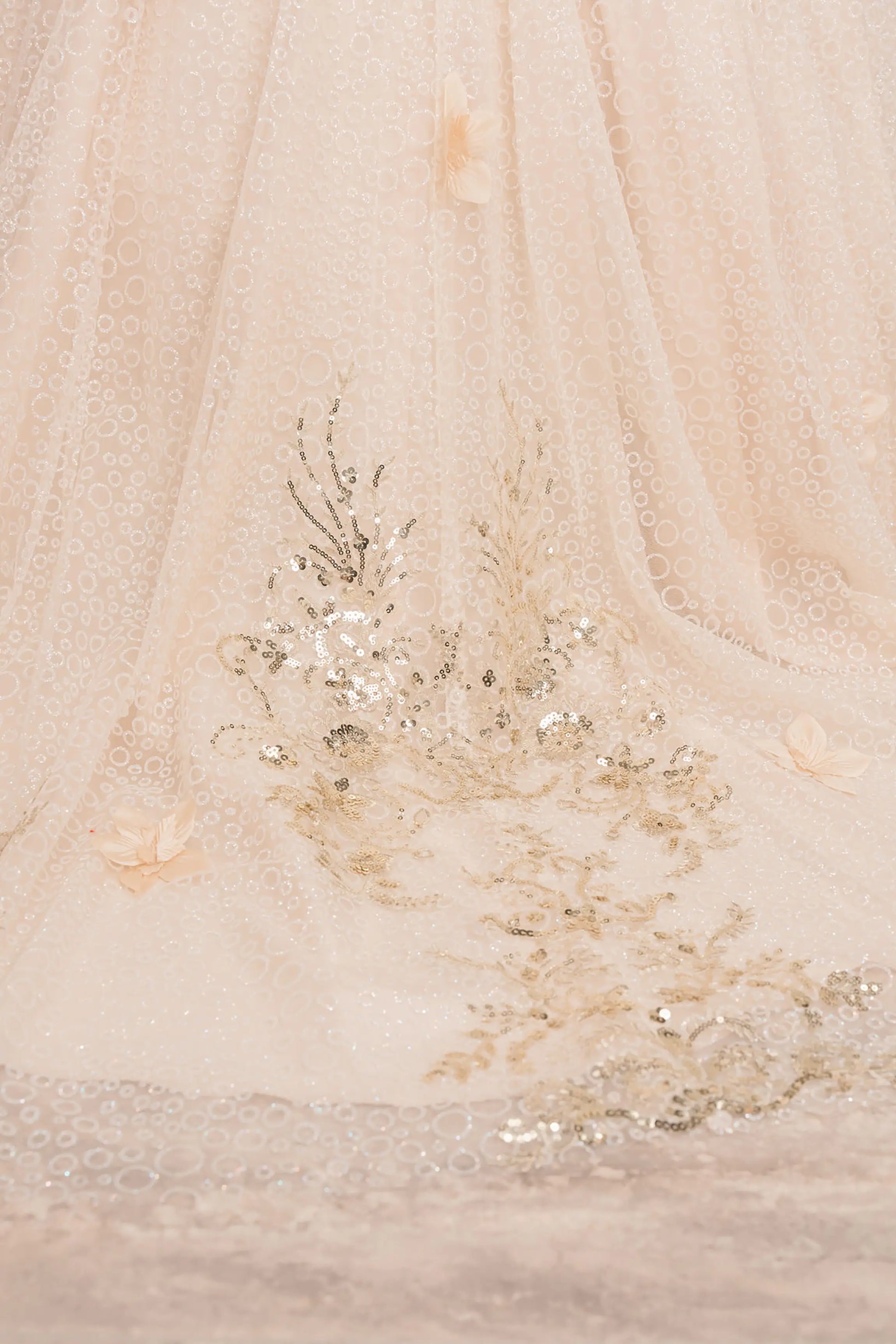 Close up view of Champagne mini quince ball gown with glitter floral embroidered bodice, full skirt, lace up back, oversized bow, and sheer lace gloves