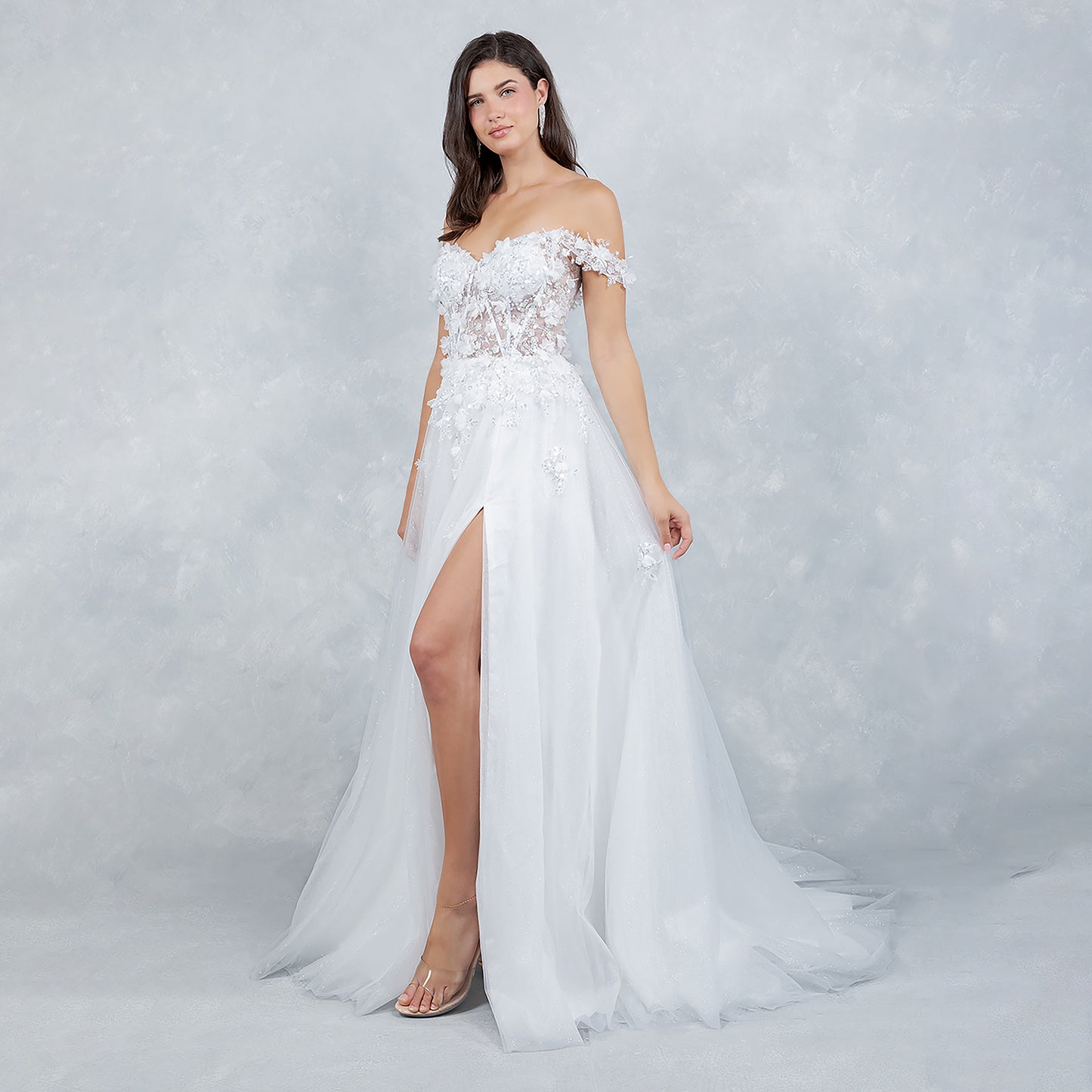 Woman wearing a white off-shoulder gown with lace details on a gray background