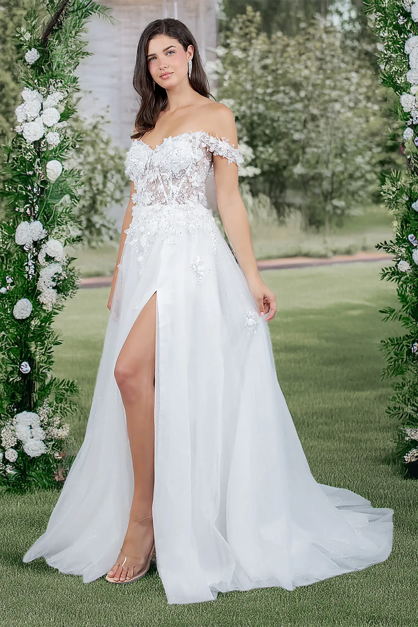 Woman in a white off-shoulder gown with floral details standing in front of floral arches.