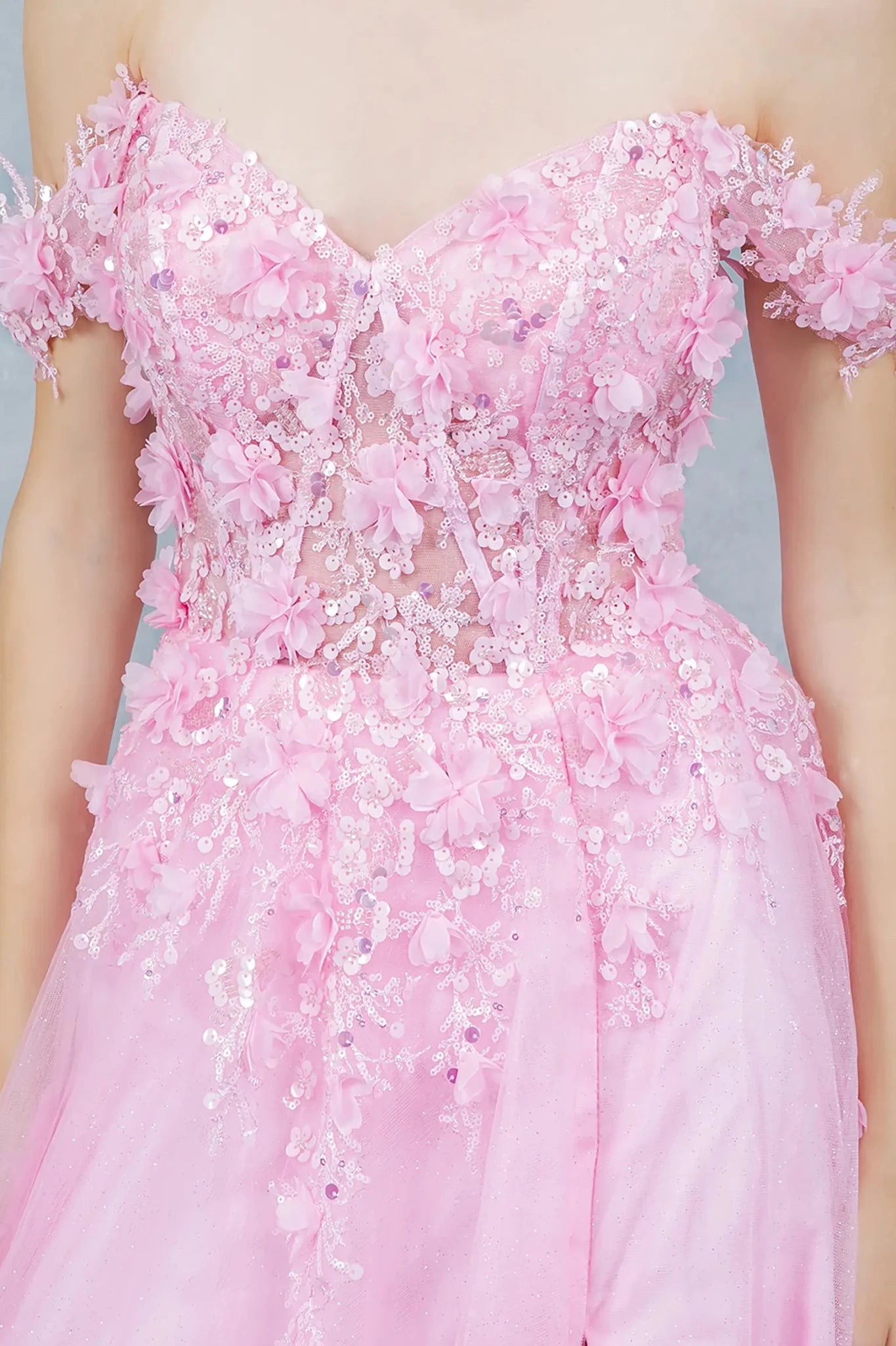 A close-up view of a woman wearing a pink floral lace corset bodice with sequin detail.