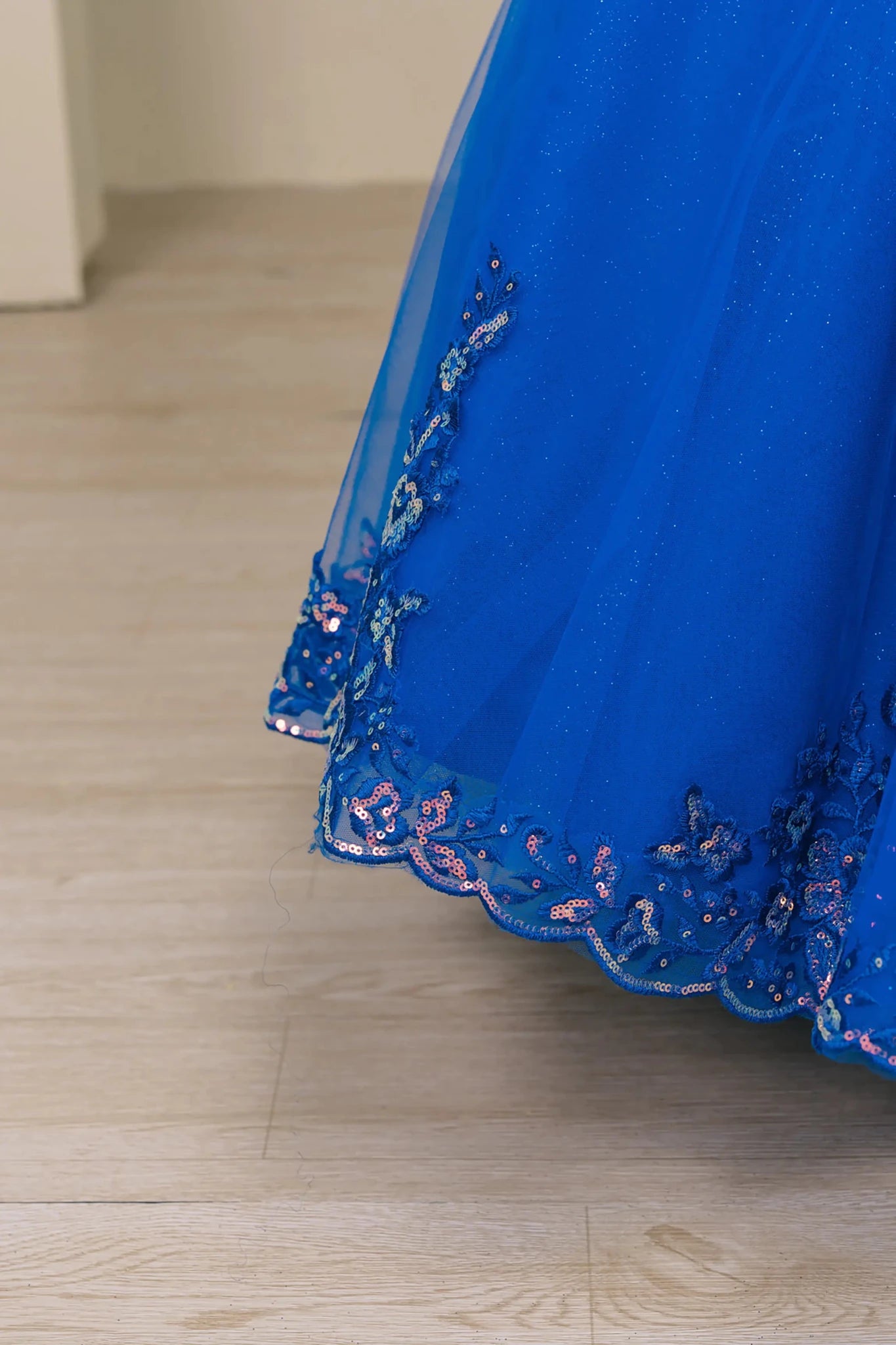 Close up view Royal mini quince off shoulder mini quince dress with embroidered bodice, gemstone accent, glitter tulle skirt detail.