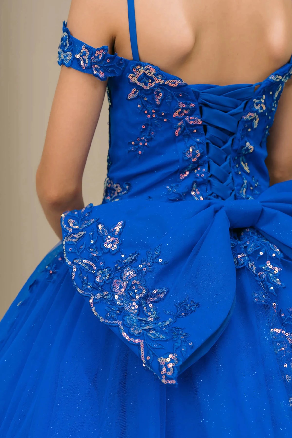 Back close-up view Royal mini quince off shoulder mini quince dress with embroidered bodice, gemstone accent, glitter tulle skirt, lace up back, and oversized bow.