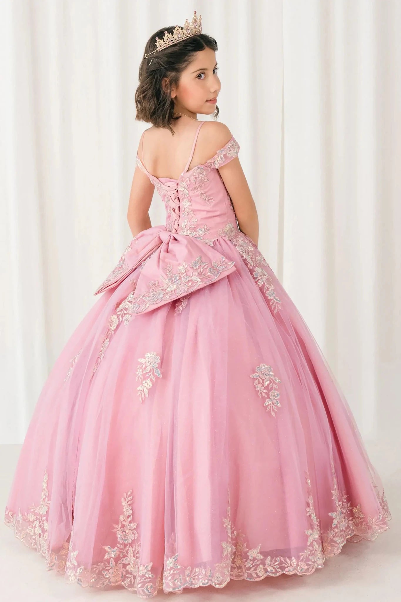 Back full-length view of Dusty Rose mini quince off shoulder mini quince dress with embroidered bodice, gemstone accent, glitter tulle skirt, lace up back, and oversized bow.