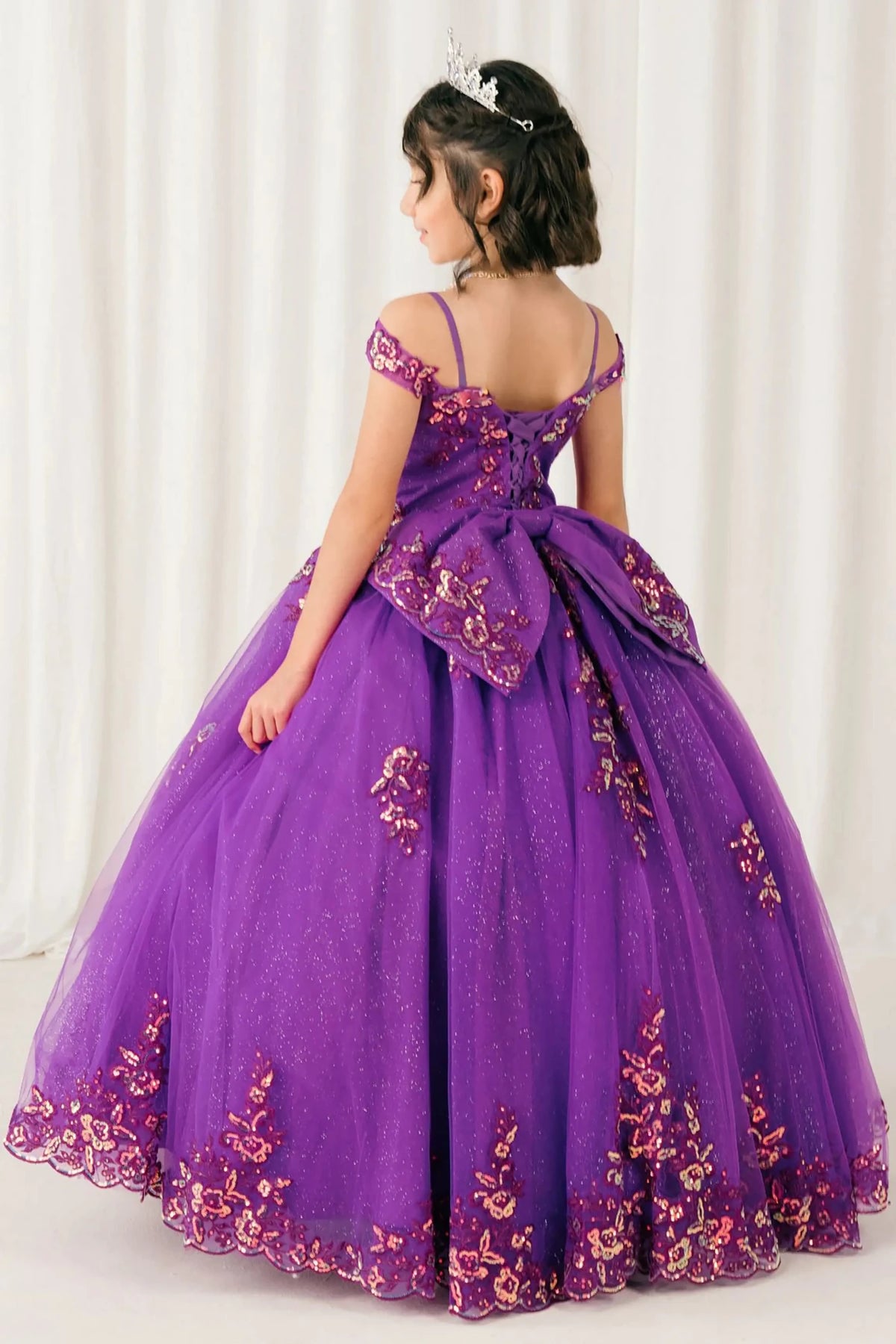 Front full-length view of Magenta Rose mini quince off shoulder mini quince dress with embroidered bodice, gemstone accent, glitter tulle skirt, lace up back, and oversized bow.