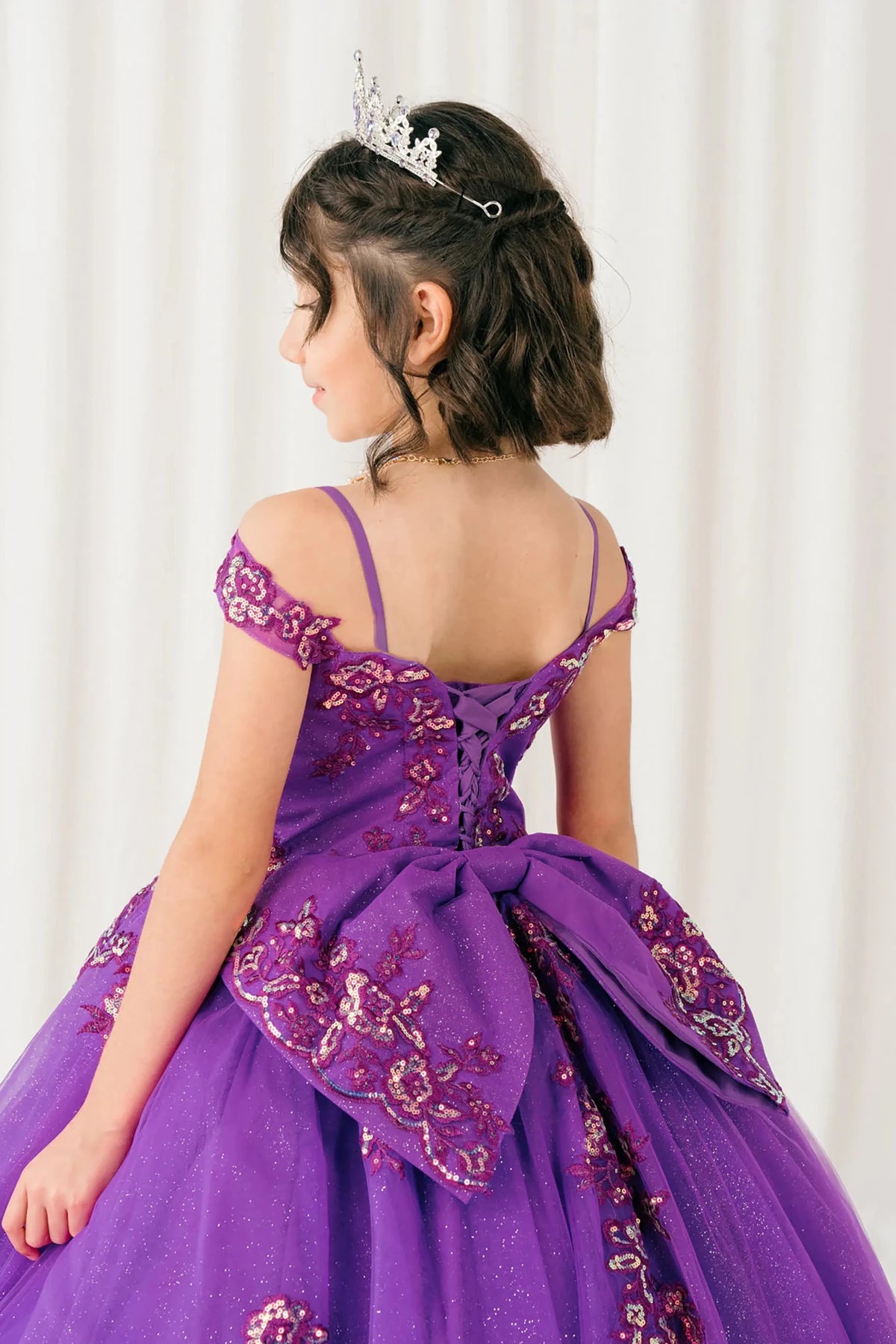 Back close-up Magenta Rose mini quince off shoulder mini quince dress with embroidered bodice, gemstone accent, glitter tulle skirt, lace up back, and oversized bow.
