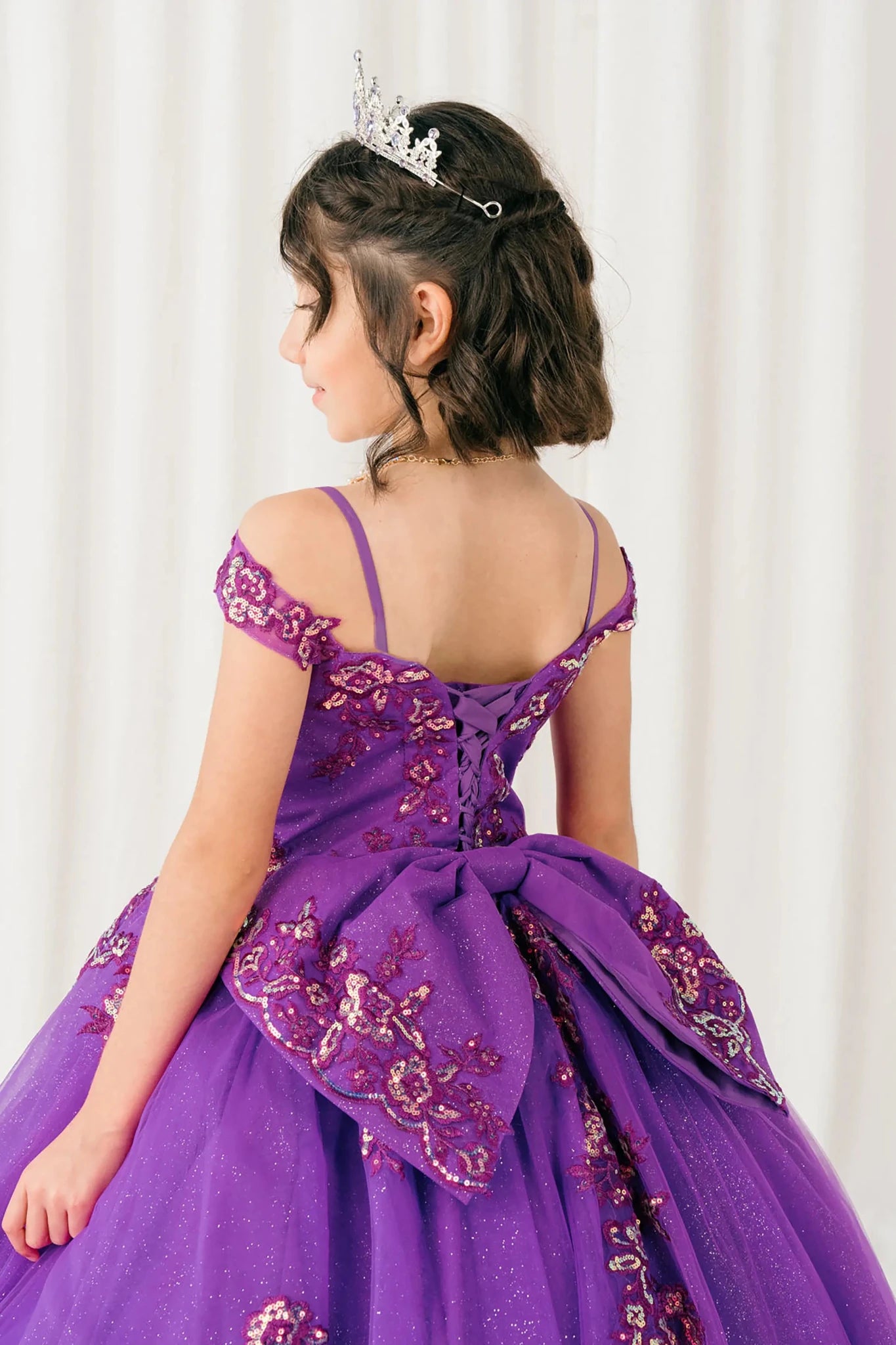 Back close-up Magenta Rose mini quince off shoulder mini quince dress with embroidered bodice, gemstone accent, glitter tulle skirt, lace up back, and oversized bow.