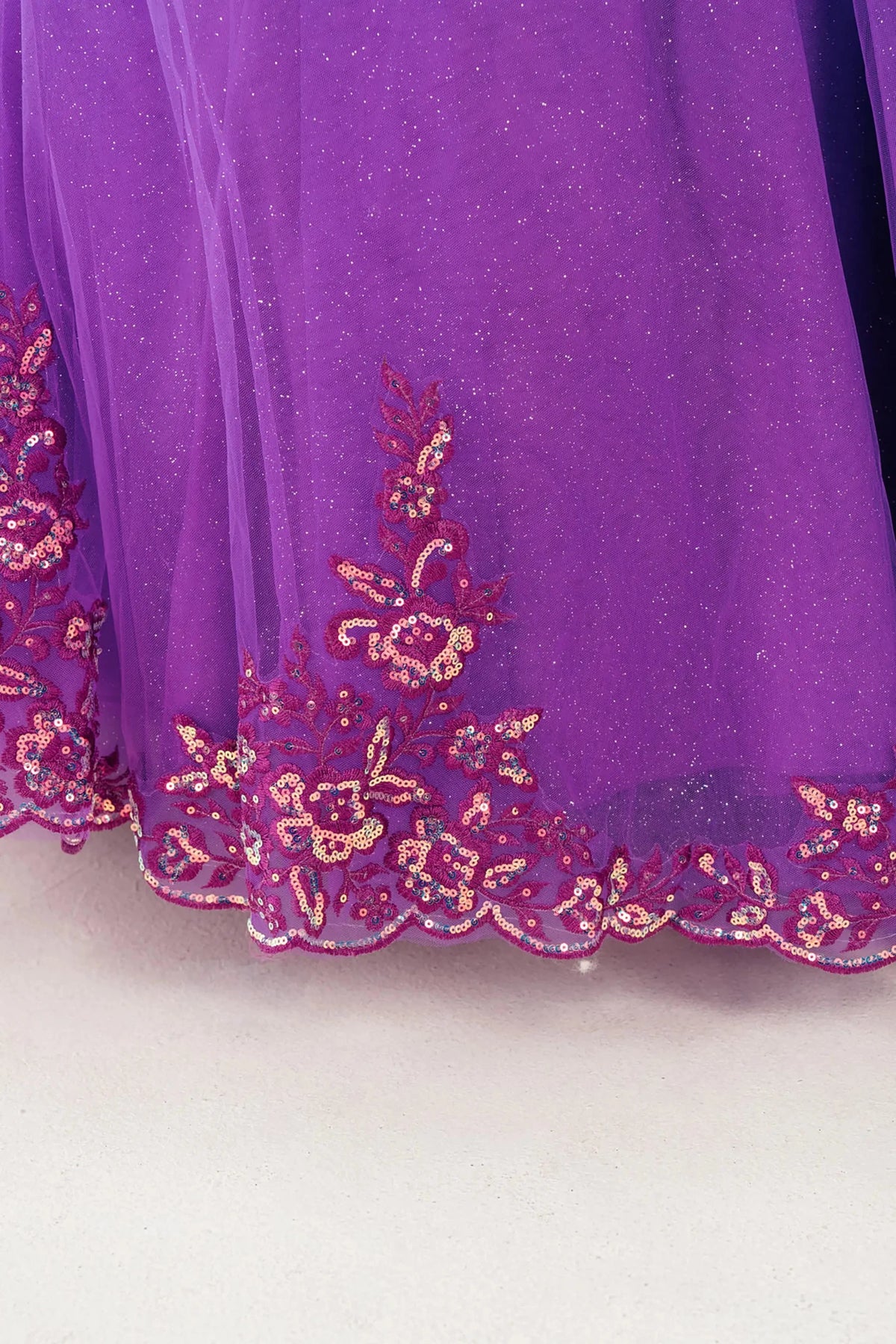 Close up Magenta Rose mini quince off shoulder mini quince dress with embroidered bodice, gemstone accent, glitter tulle skirt detail.