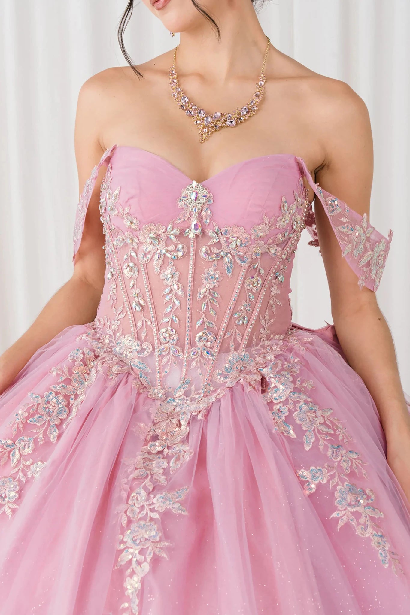Front close-up view of Dusty Rose Off shoulder quinceañera ball gown with beaded corset, floral appliqués, layered tulle skirt, cathedral length train, and bow