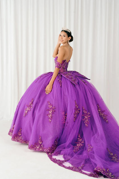 Side full-length view of Magenta Off shoulder quinceañera ball gown with beaded corset, floral appliqués, layered tulle skirt, cathedral length train, and bow