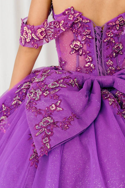 Back half close-up view of Magenta Off shoulder quinceañera ball gown with beaded corset, floral appliqués, layered tulle skirt, cathedral length train, and bow
