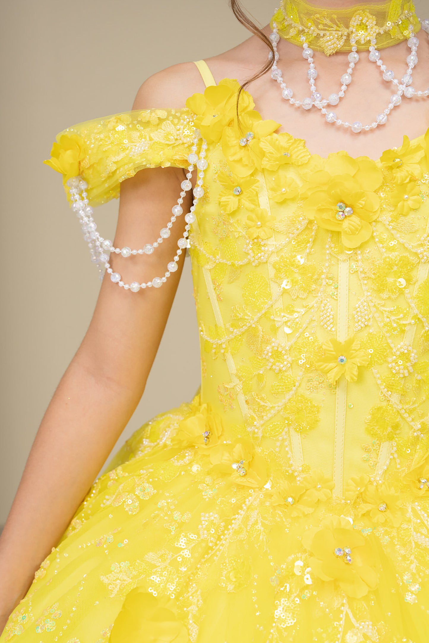 Yellow floral dress with pearl accessories on a neutral background