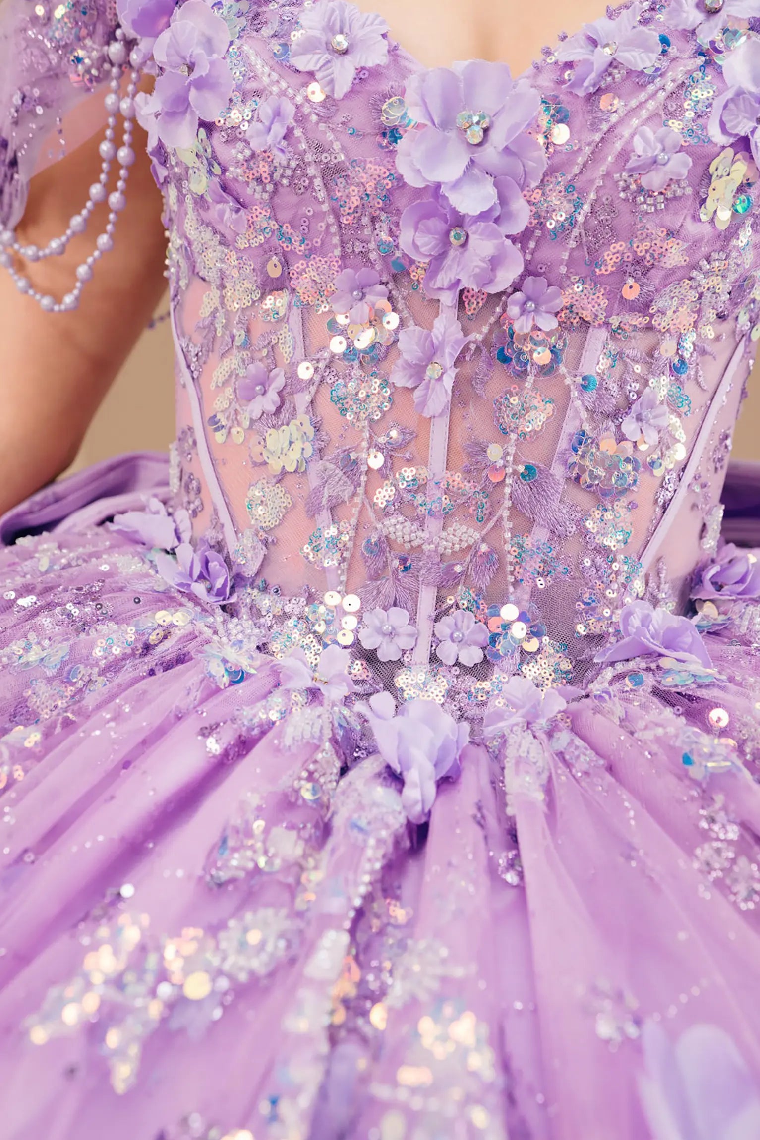 Bodice close-up of a woman wearing lilac quinceañera dress showing floral appliques, sequins, and intricate beadwork details.
