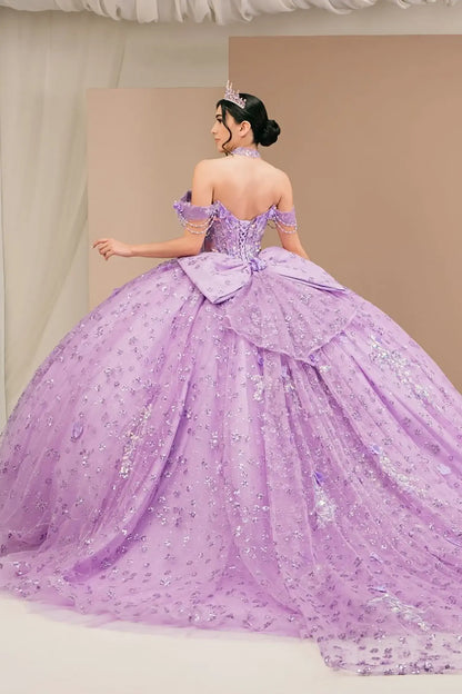 Back view of a woman wearing lilac quinceañera dress with voluminous glitter tulle skirt, lace-up corset closure, and floral applique accents.