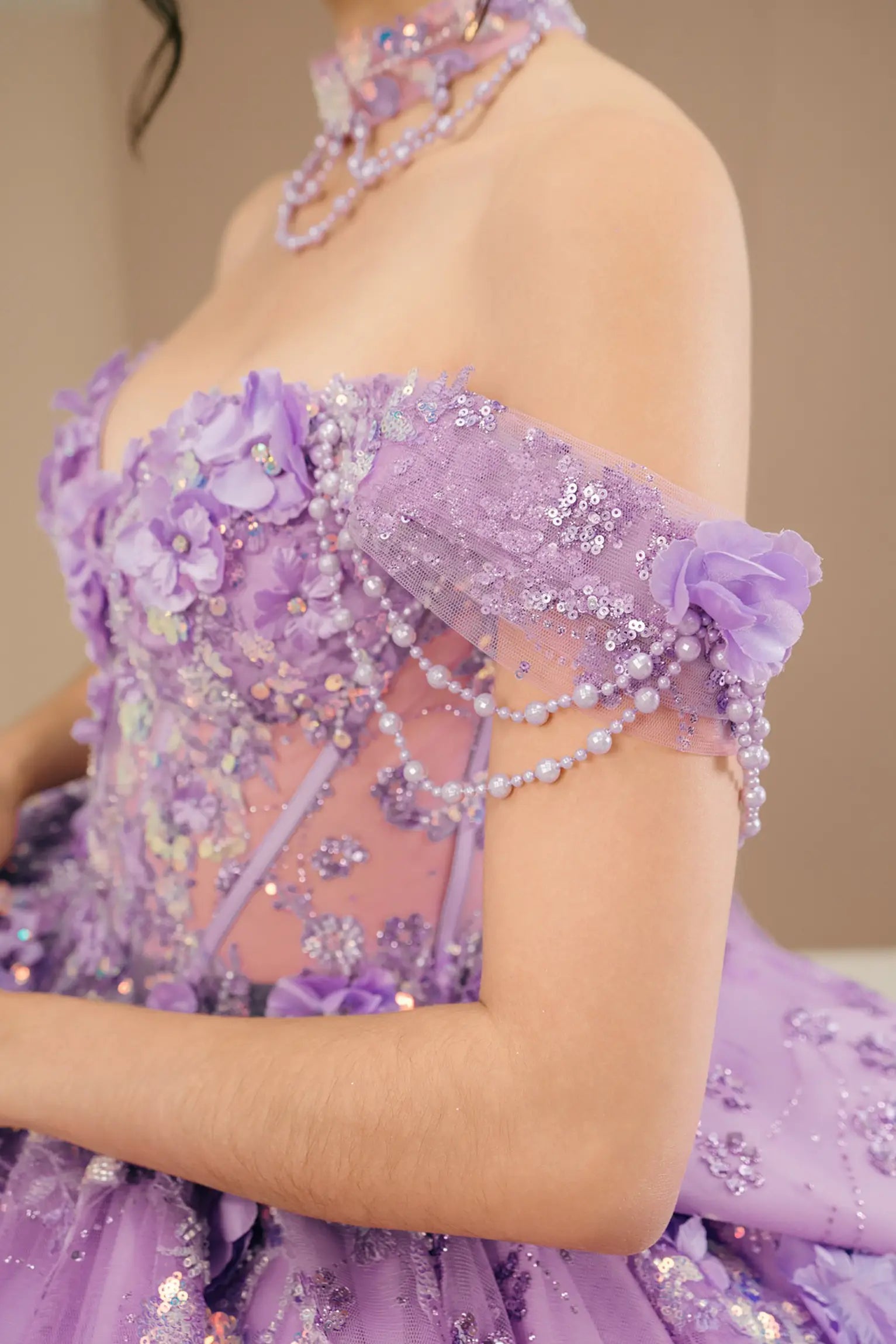 Side close-up view of a woman wearing lilac quinceañera dress highlighting layered glitter tulle, sweetheart neckline, and embellished bodice.