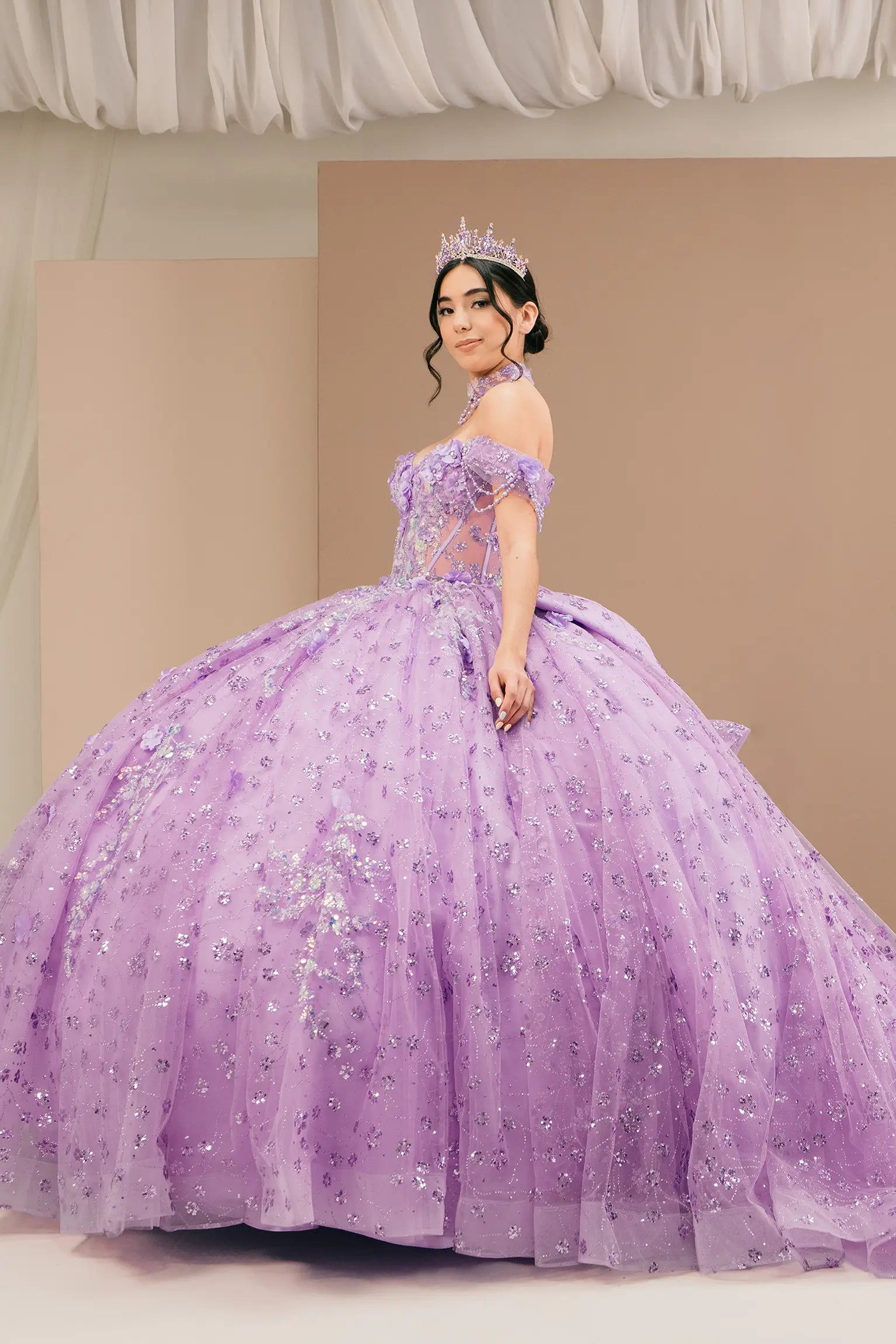 Side view of a woman wearing lilac quinceañera dress highlighting layered glitter tulle, sweetheart neckline, and embellished bodice.