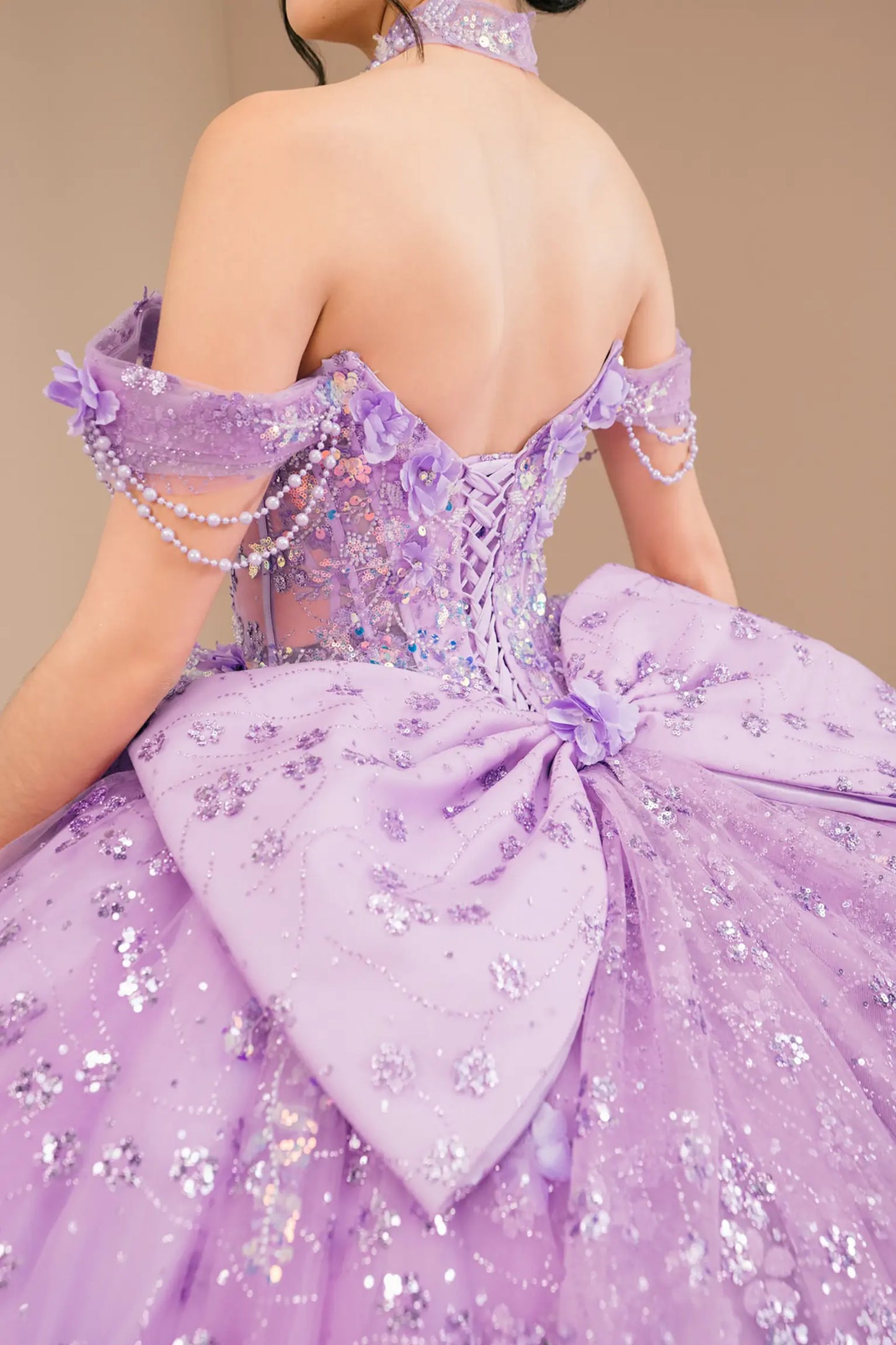 Bodice back close-up of a woman wearing lilac quinceañera dress with beadwork detail, sequins, and lace-up corset design.