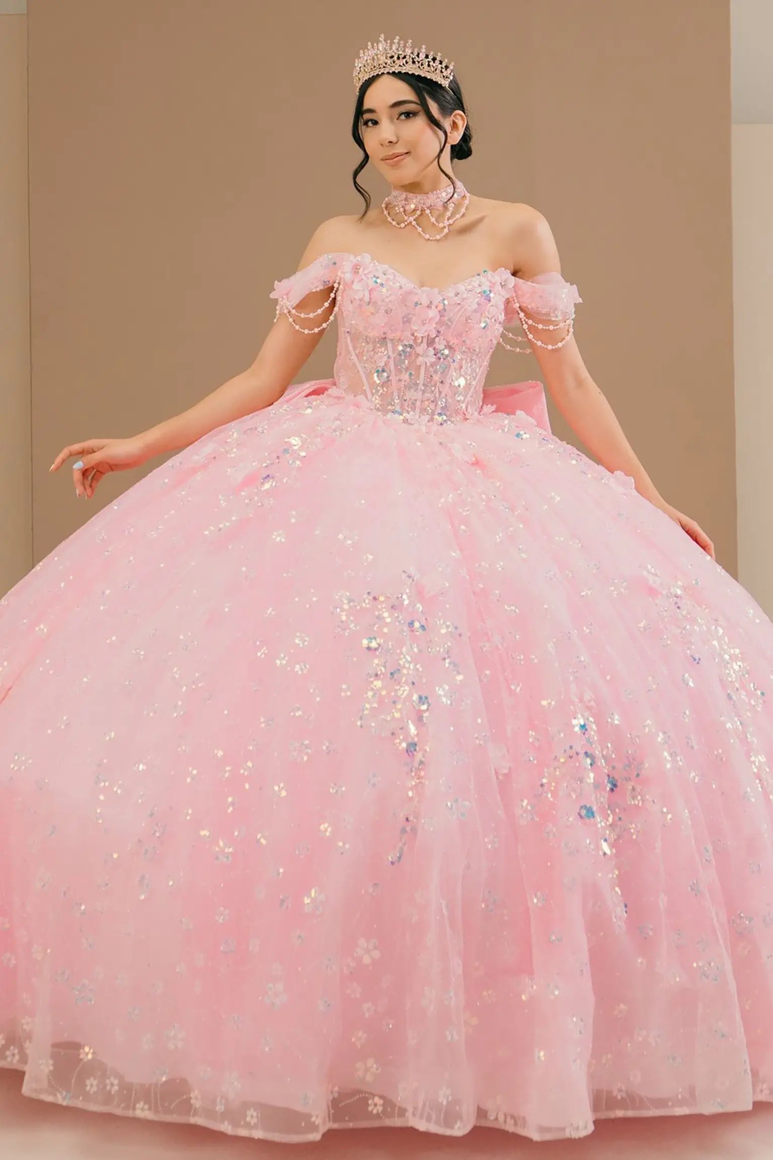 Full front view of a woman wearing pink quinceañera dress with glitter tulle skirt, off-shoulder sweetheart neckline, and beaded corset bodice.