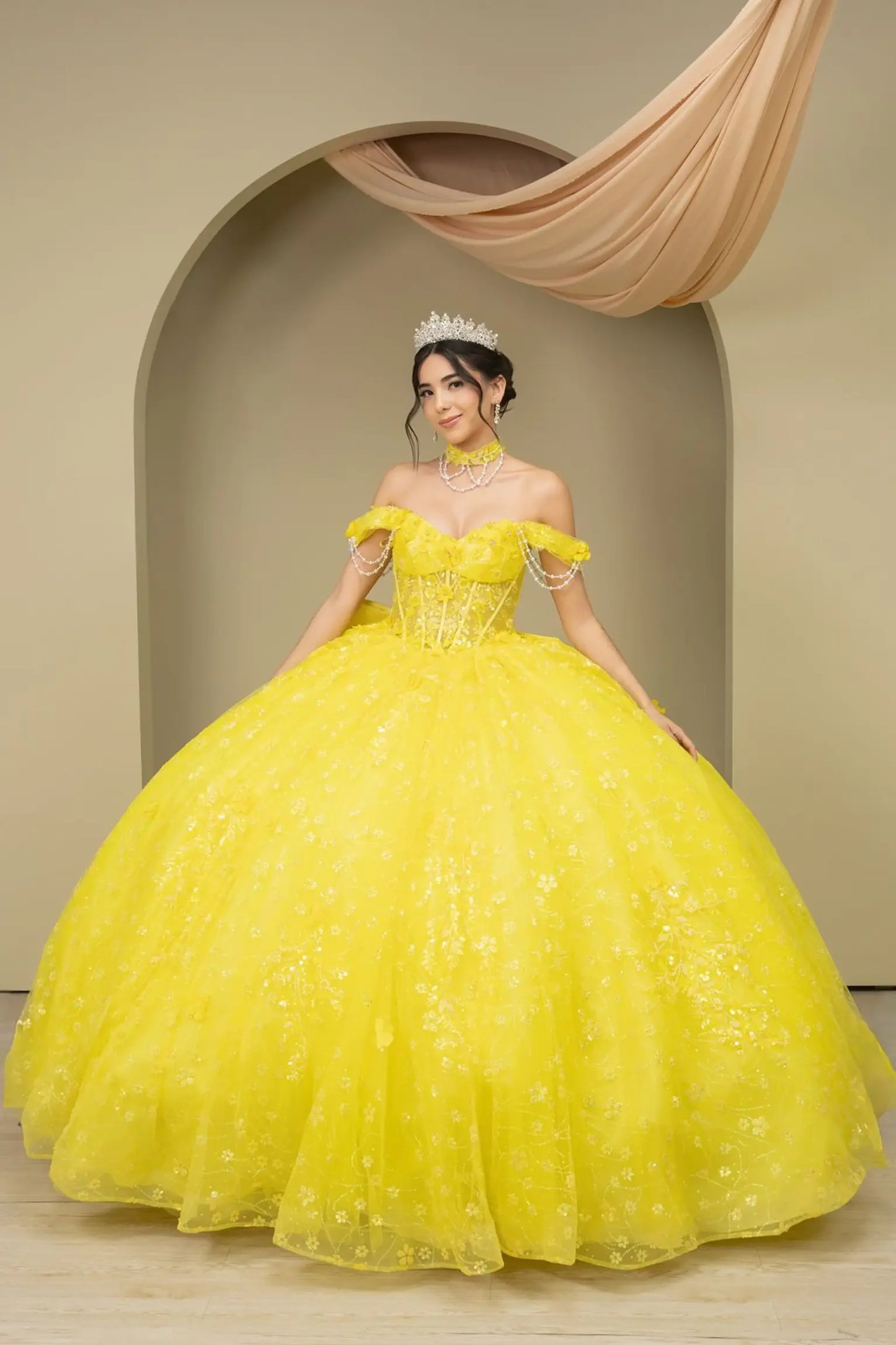 Front view of a woman wearing yellow quinceañera dress with beadwork detail, sequins, and lace-up corset design.