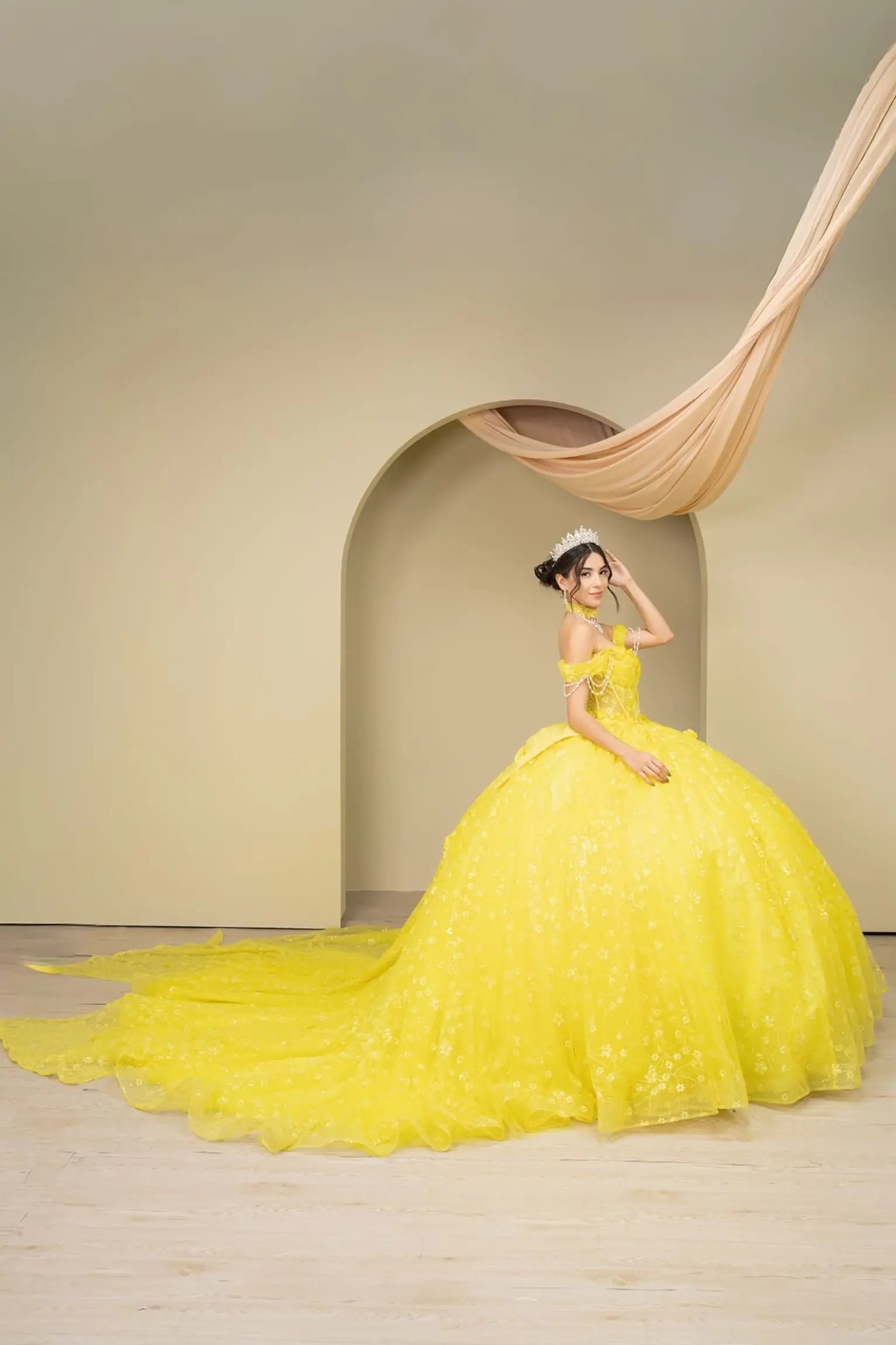 Full side view of a woman wearing yellow quinceañera dress with glitter tulle skirt, sweetheart neckline, and beaded corset bodice.