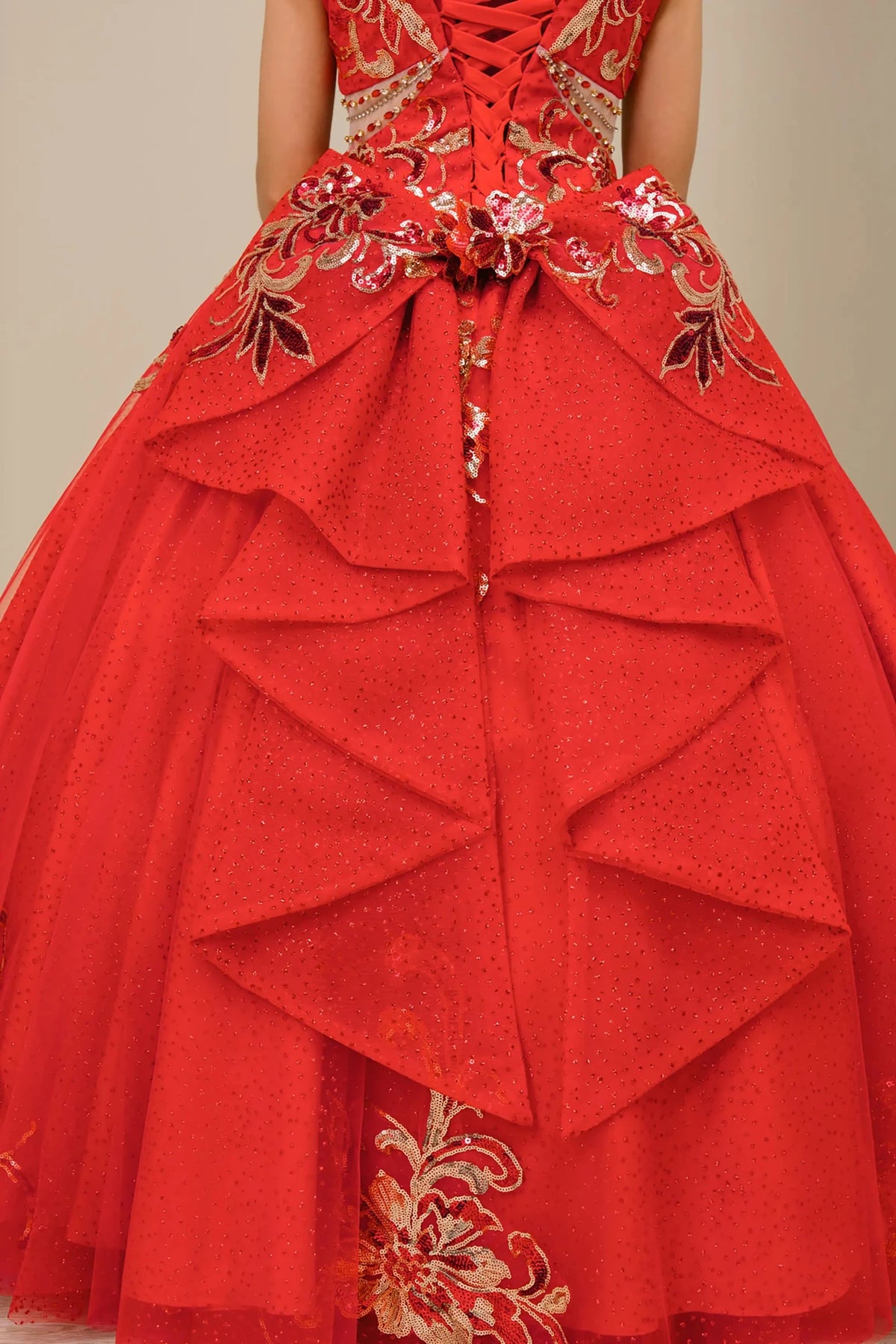 Close up view of Red mini quince mini quince dress with embroidered bodice, glitter tulle skirt, lace up back, and layered bow.