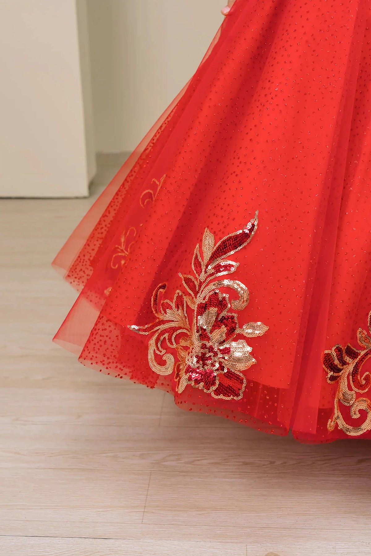 Close up view of Red mini quince mini quince dress with off shoulder floral embroidered bodice, glitter tulle skirt detail.