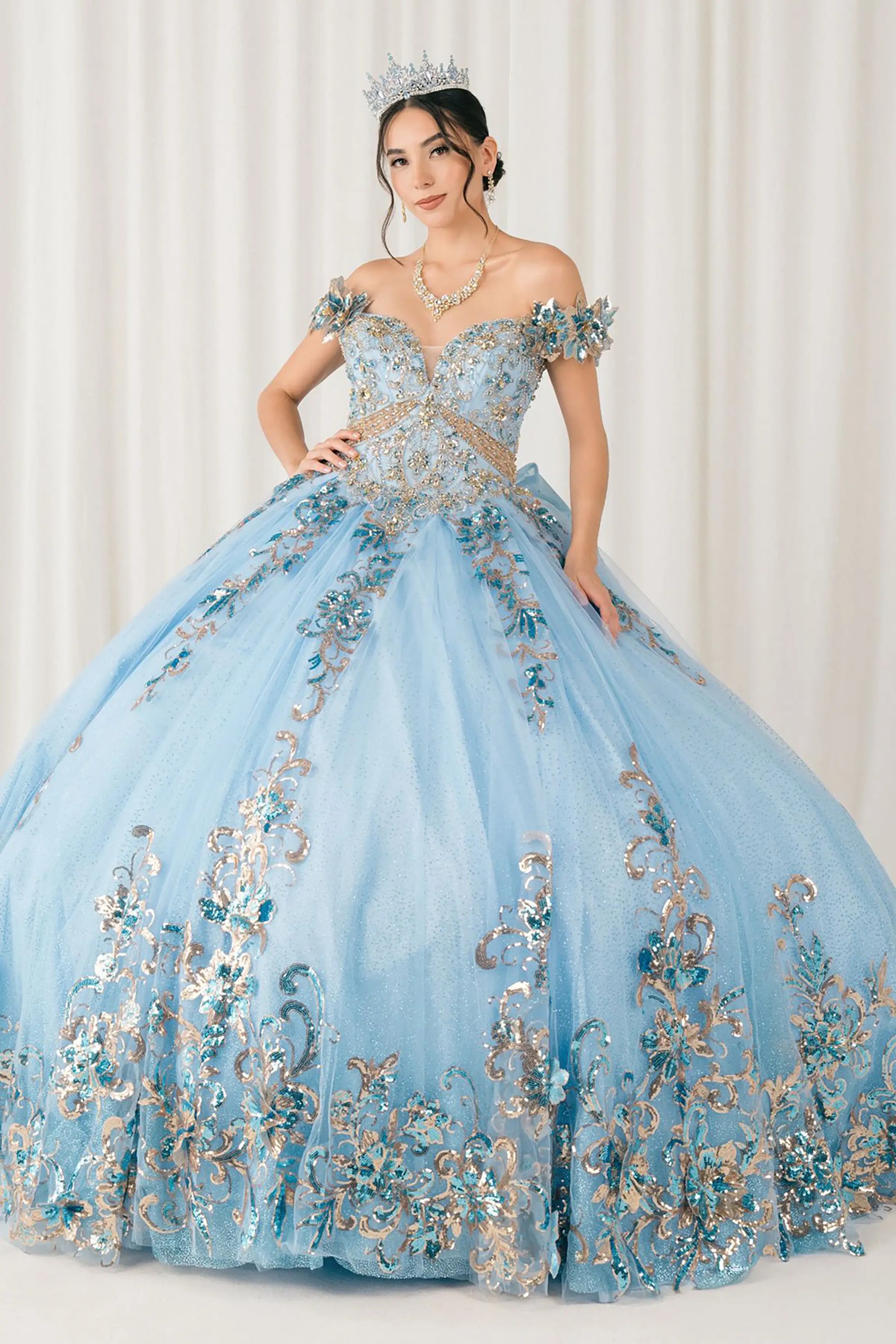 Front full-length view of Blue quinceañera ball gown with off shoulder bodice, gold embroidery, floral appliqués, voluminous tulle skirt, corset back, and oversized bow