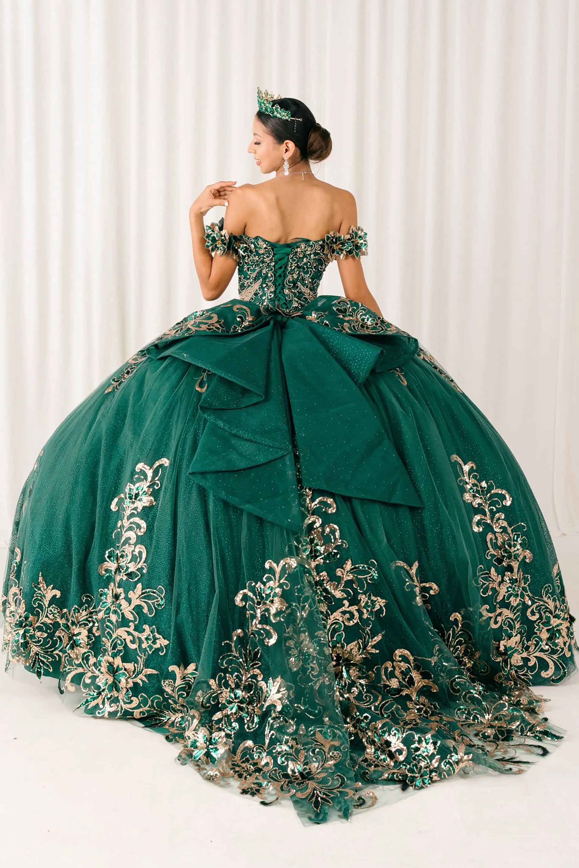 Back full-length view of Hunter Green quinceañera ball gown with off shoulder bodice, gold embroidery, floral appliqués, voluminous tulle skirt, corset back, and oversized bow