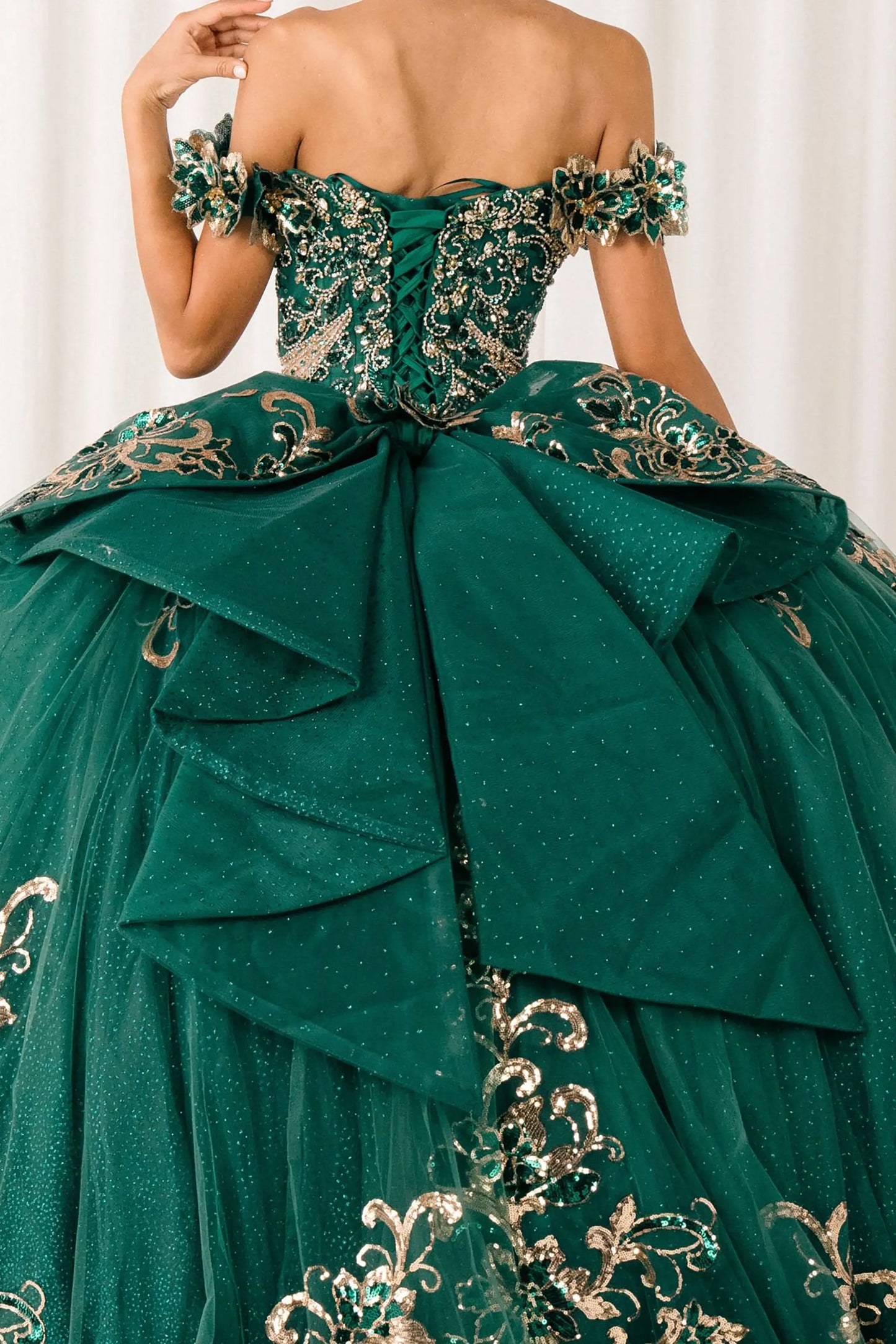 Black close-up Blue Hunter Green quinceañera ball gown with off shoulder bodice, gold embroidery, floral appliqués, voluminous tulle skirt, corset back, and oversized bow