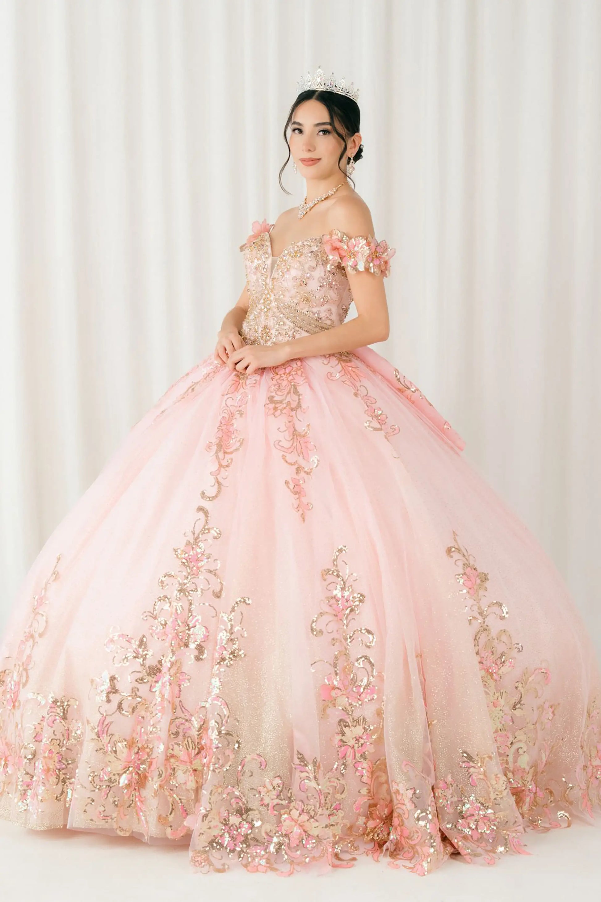 Front full-length view of Pink quinceañera ball gown with off shoulder bodice, gold embroidery, floral appliqués, voluminous tulle skirt, corset back, and oversized bow