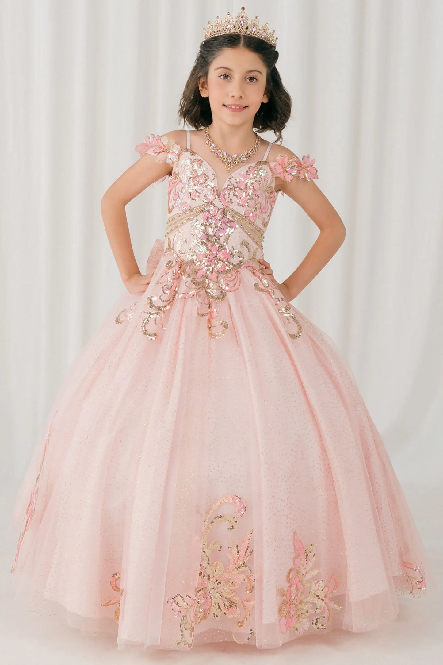 Front full-length view of Pink mini quince ball gown with off shoulder floral embroidered bodice, glitter tulle skirt, lace up back, and layered bow