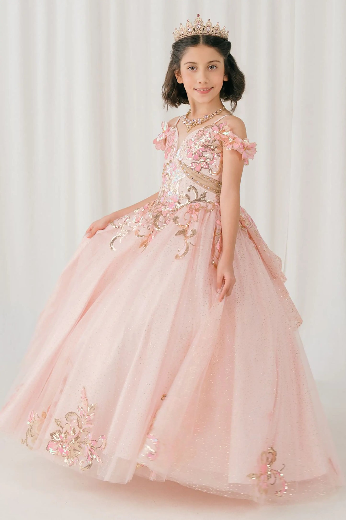 Side full-length view of Pink mini quince ball gown with off shoulder floral embroidered bodice, glitter tulle skirt, lace up back, and layered bow