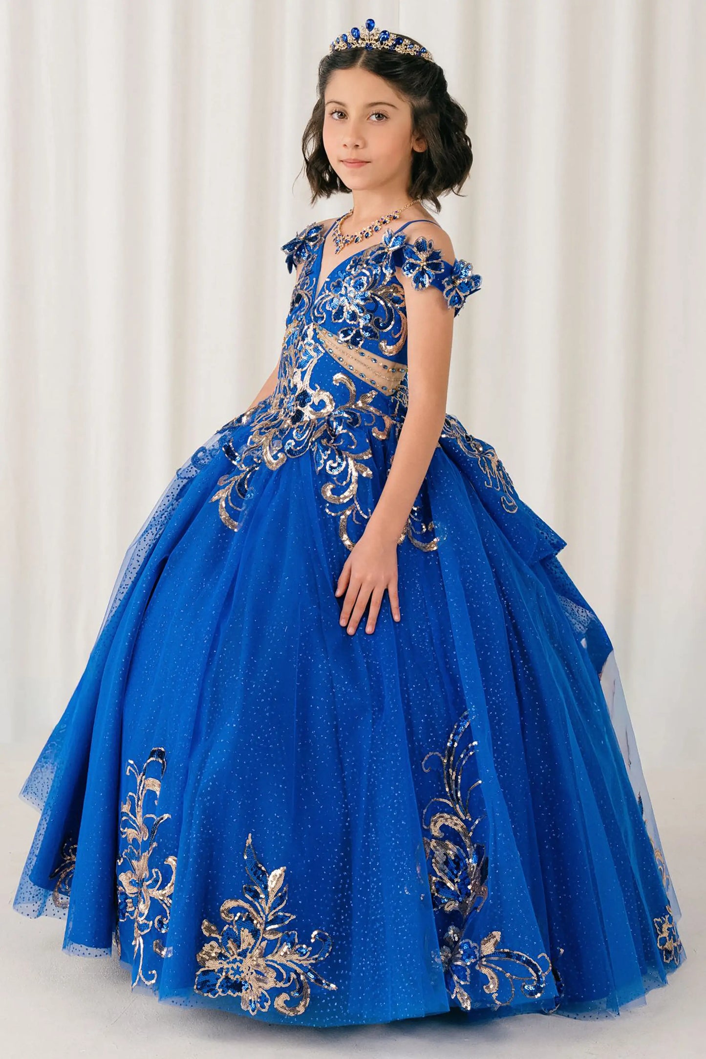 Side full-length view of Royal mini quince ball gown with off shoulder floral embroidered bodice, glitter tulle skirt, lace up back, and layered bow