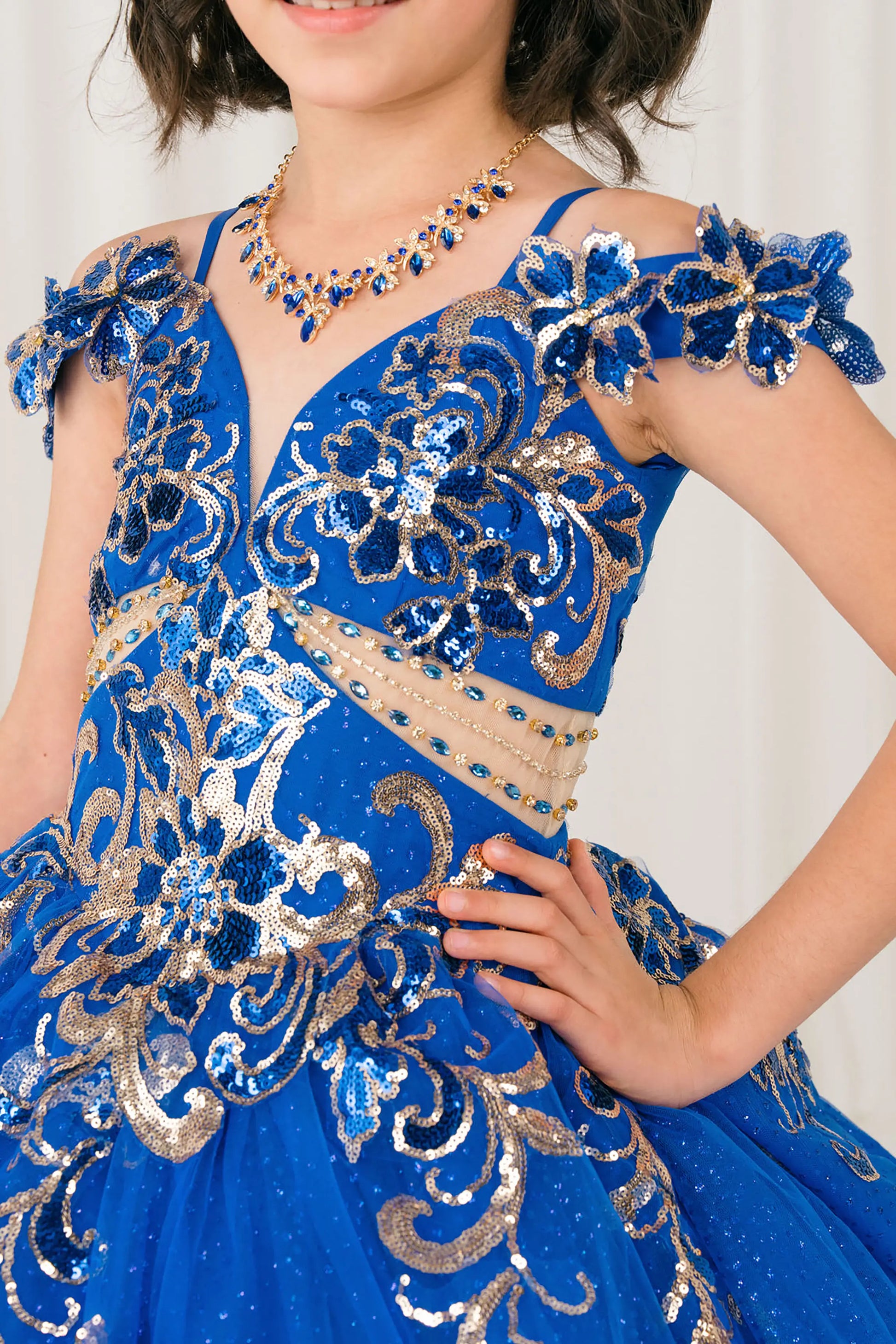 Front close up view of Royal mini quince ball gown with off shoulder floral embroidered bodice, glitter tulle skirt, lace up back, and layered bow