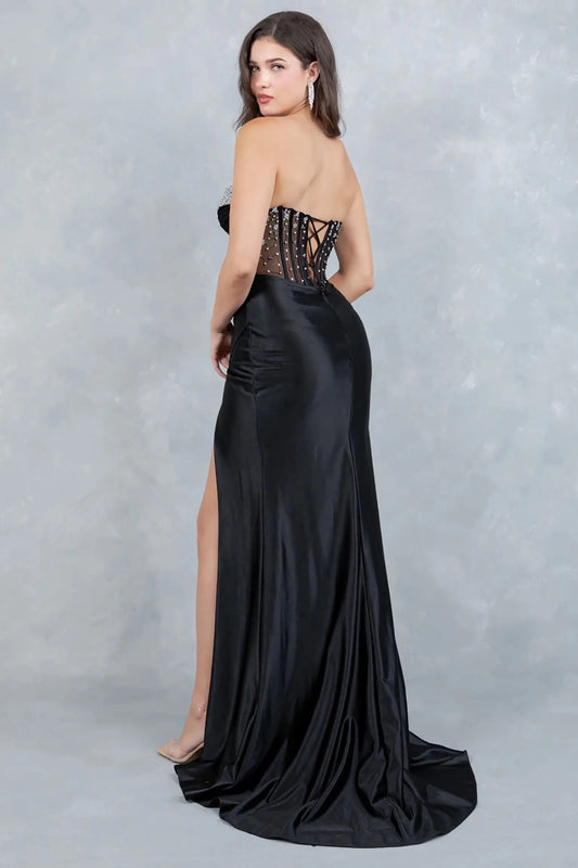 A full-length view of a woman wearing black formal prom dress with a lace-up corset and sweeping train.