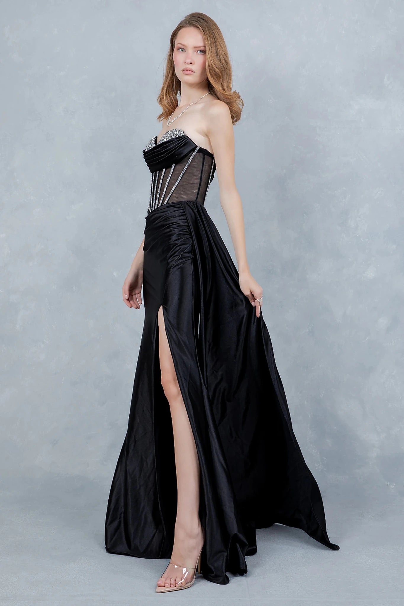 Black evening gown styled with high side slit and ruching at waist for flattering fit
