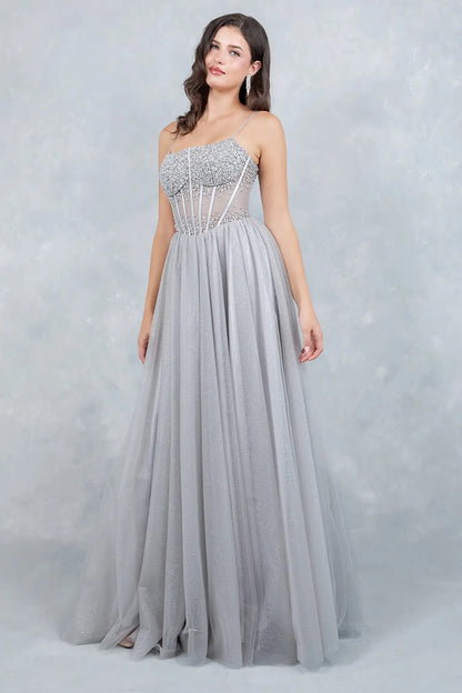 A side profile view of a woman wearing a silver prom dress, showcasing the sculpted waist and dramatic tulle volume.