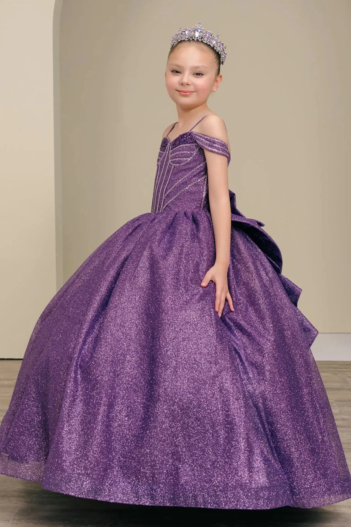 Side view of purple mini quince dress with oversized tiered bow detail, shimmering bodice, and flowing layered skirt.