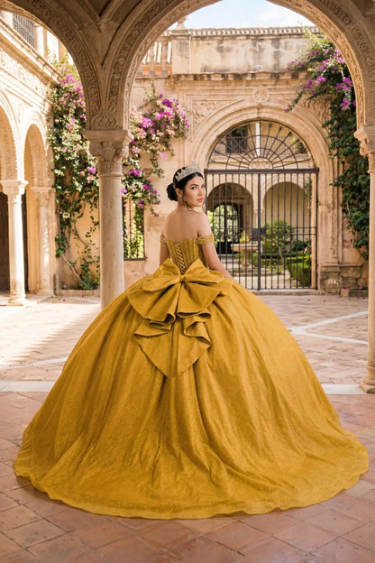 Woman back-facing in gold off-shoulder ball gown with lace-up corset bodice, intricate beadwork, glitter tulle, and cascading full skirt