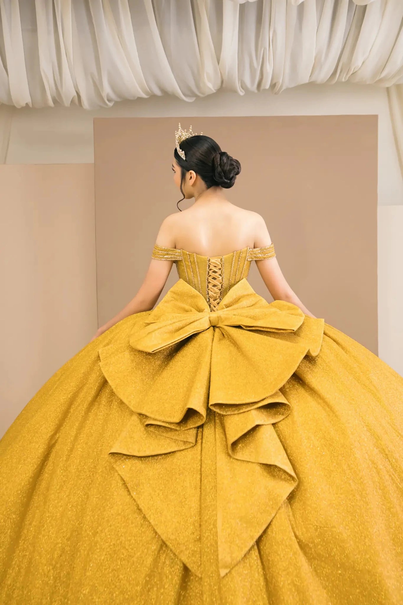 Close-up of gold ball gown fabric with intricate beadwork and sparkling glitter tulle texture