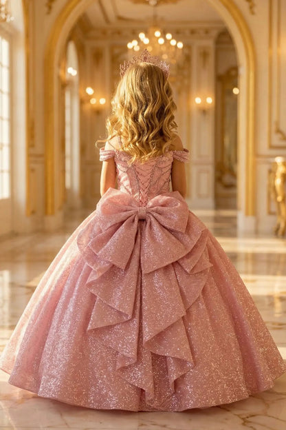 Kid back-facing in rose gold mini quince dress with lace-up corset bodice, shimmering ball gown skirt, and cascading layers