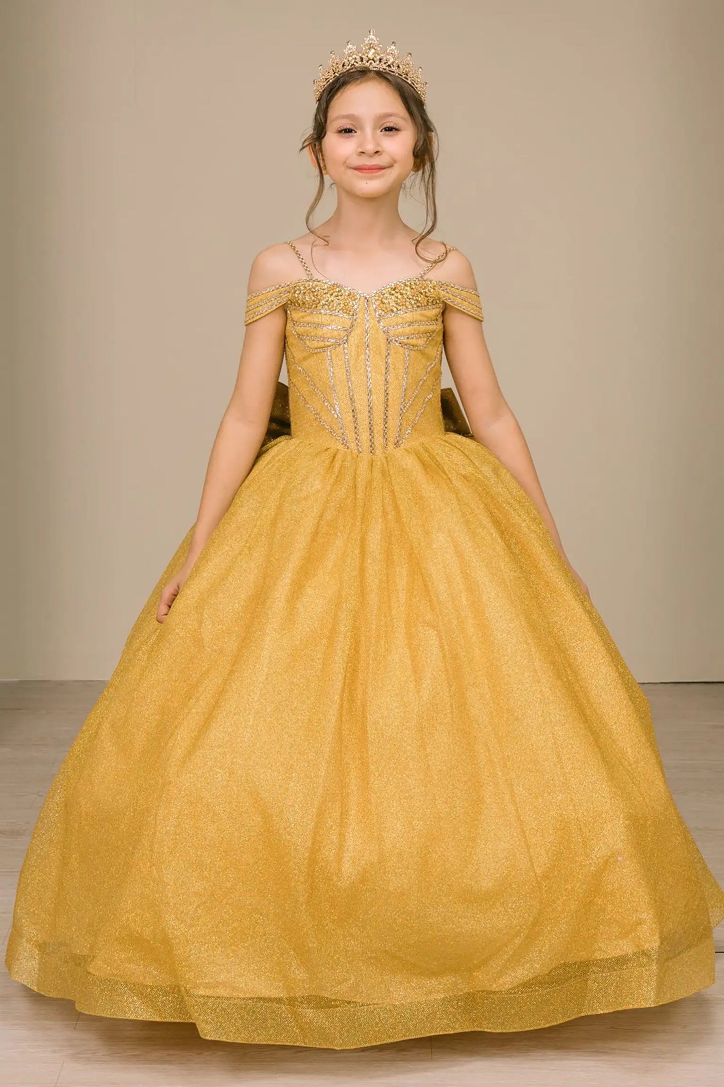 Kid standing front-facing in enchanting gold ball gown with oversized tiered bow accent, fitted bodice, and voluminous layered skirt

