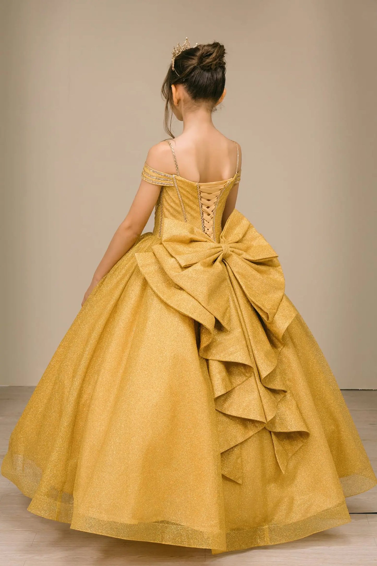 Close-up of gold ball gown fabric with shimmering tulle layers and oversized tiered bow detailing