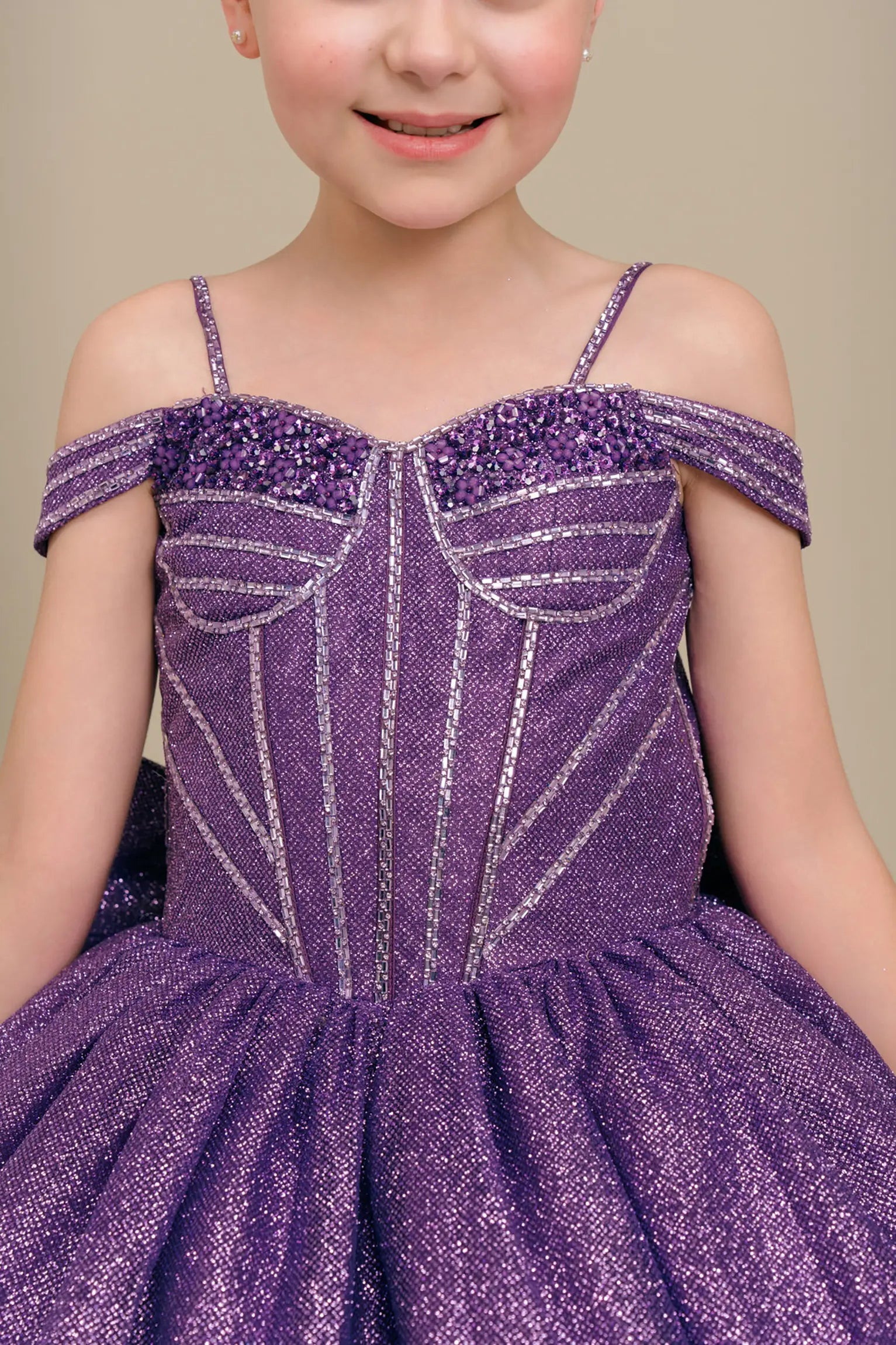 Close-up front-facing view of purple ball gown with embellished bodice and oversized tiered bow accent

