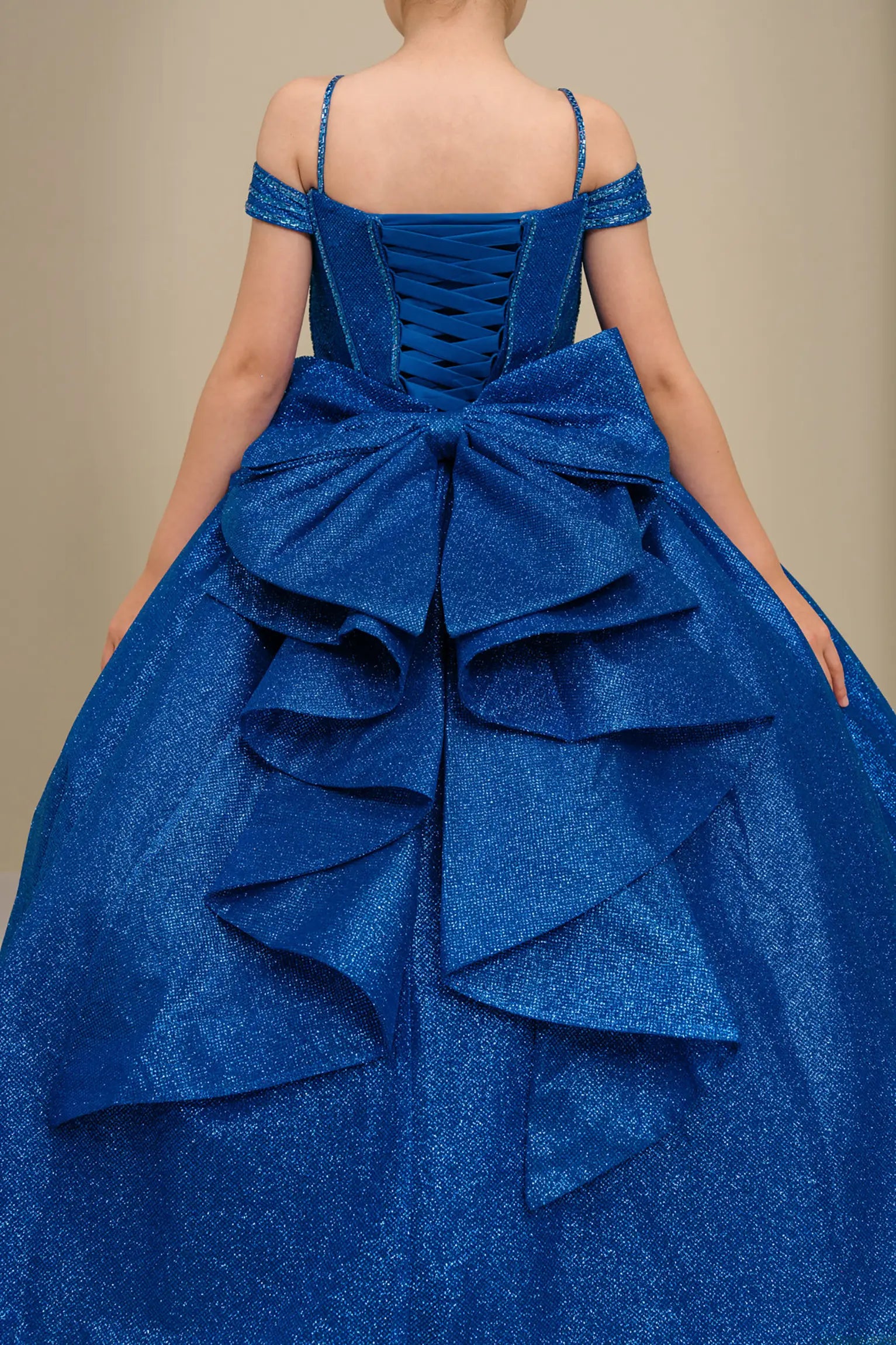 Close-up of royal blue ball gown fabric with shimmering tulle layers and oversized tiered bow detailing